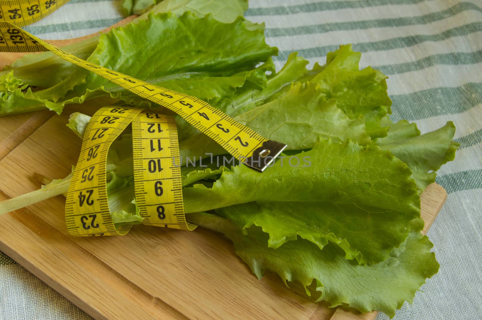 The concept of diet and healthy eating - lettuce measuring tape.