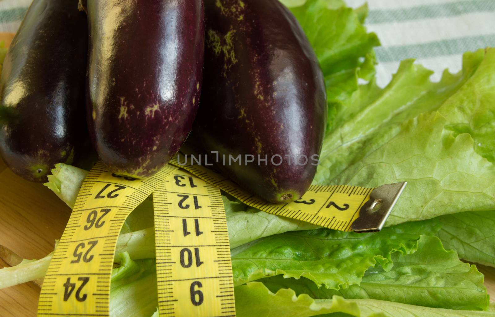 The concept of diet, healthy eating, lettuce eggplant measuring tape.