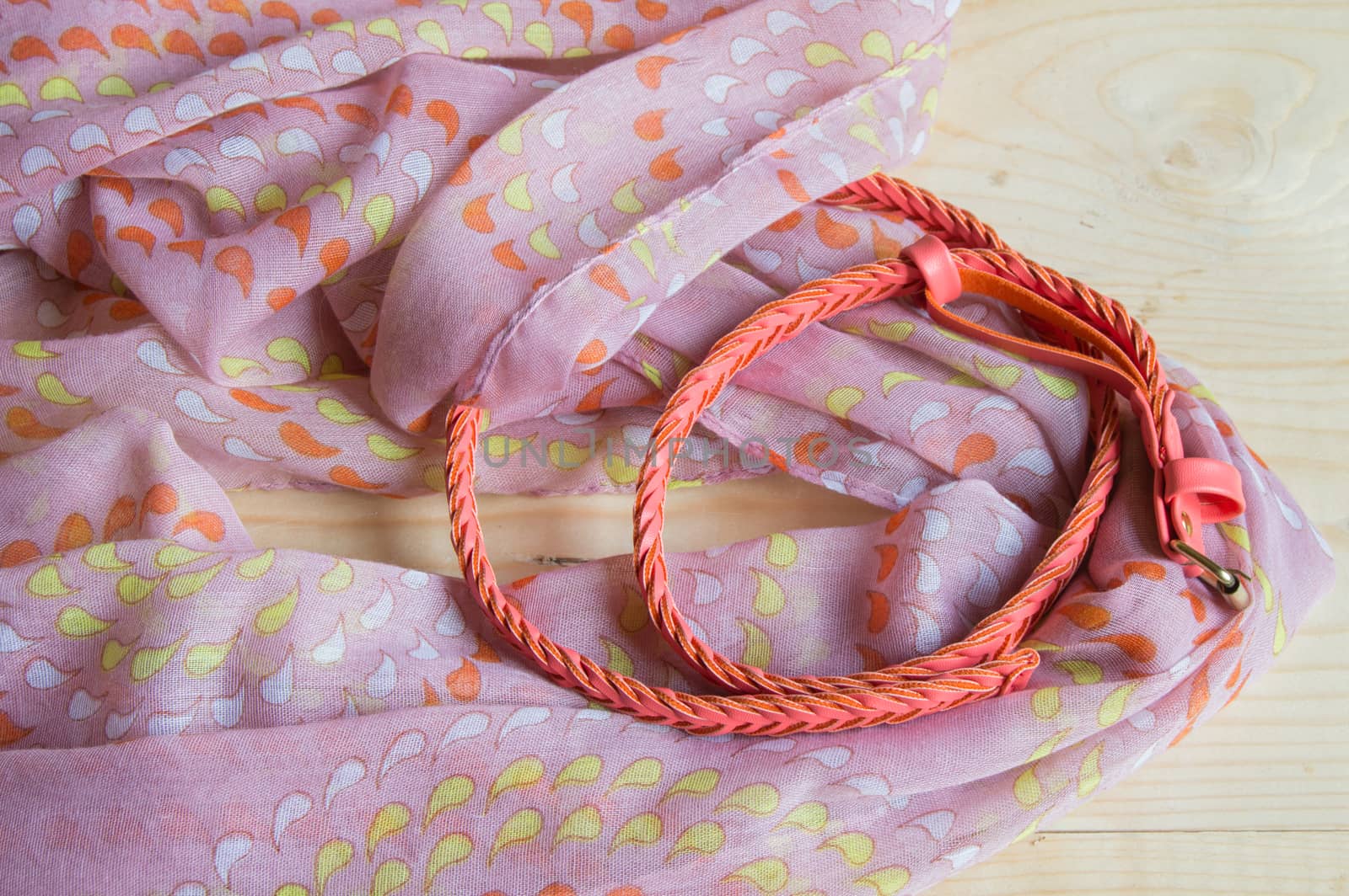 Fashionable pink accessories on wooden background - scarf, belt.