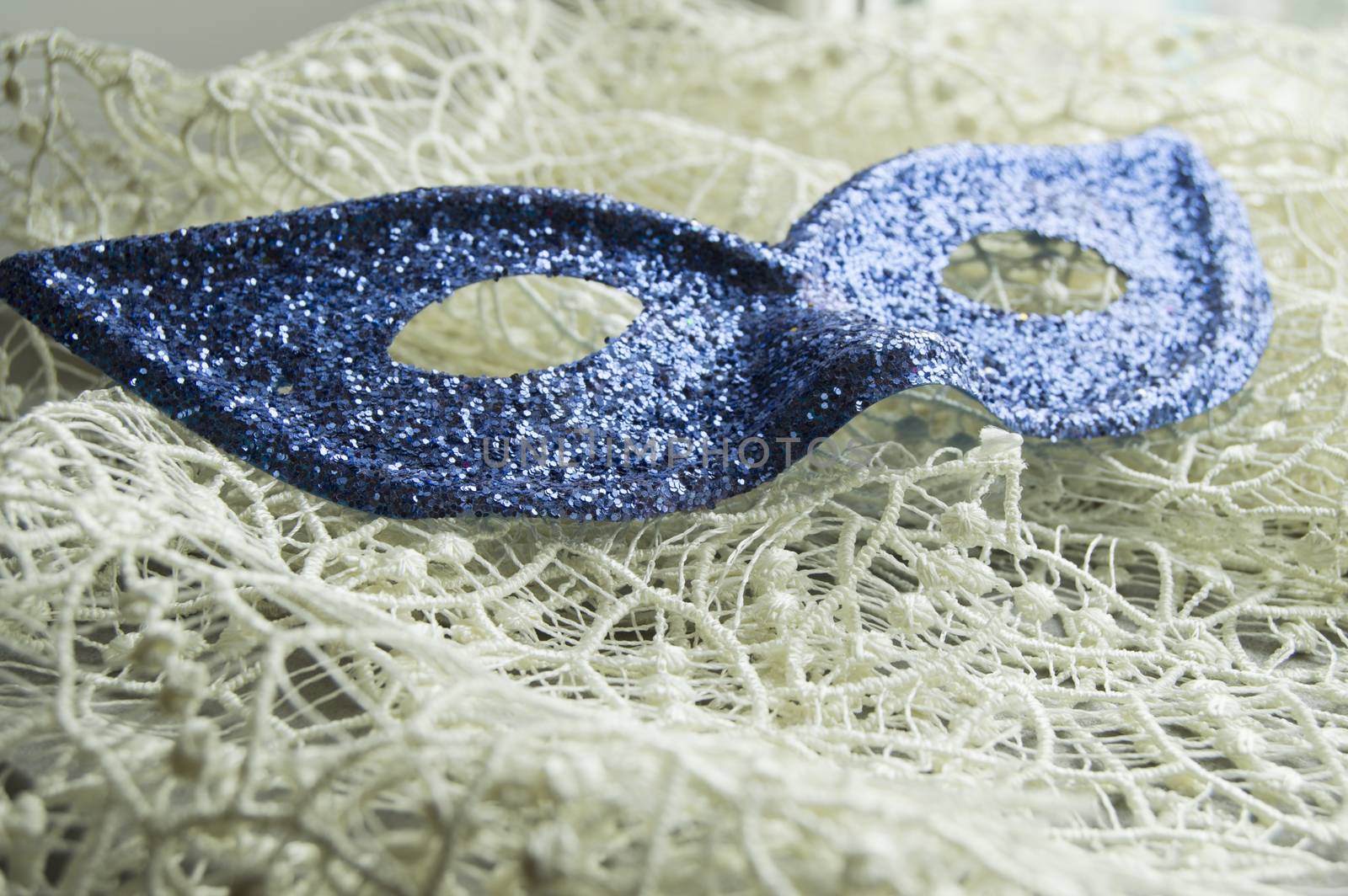 Brilliant blue carnival mask lies on beautiful lace. Fashion background.