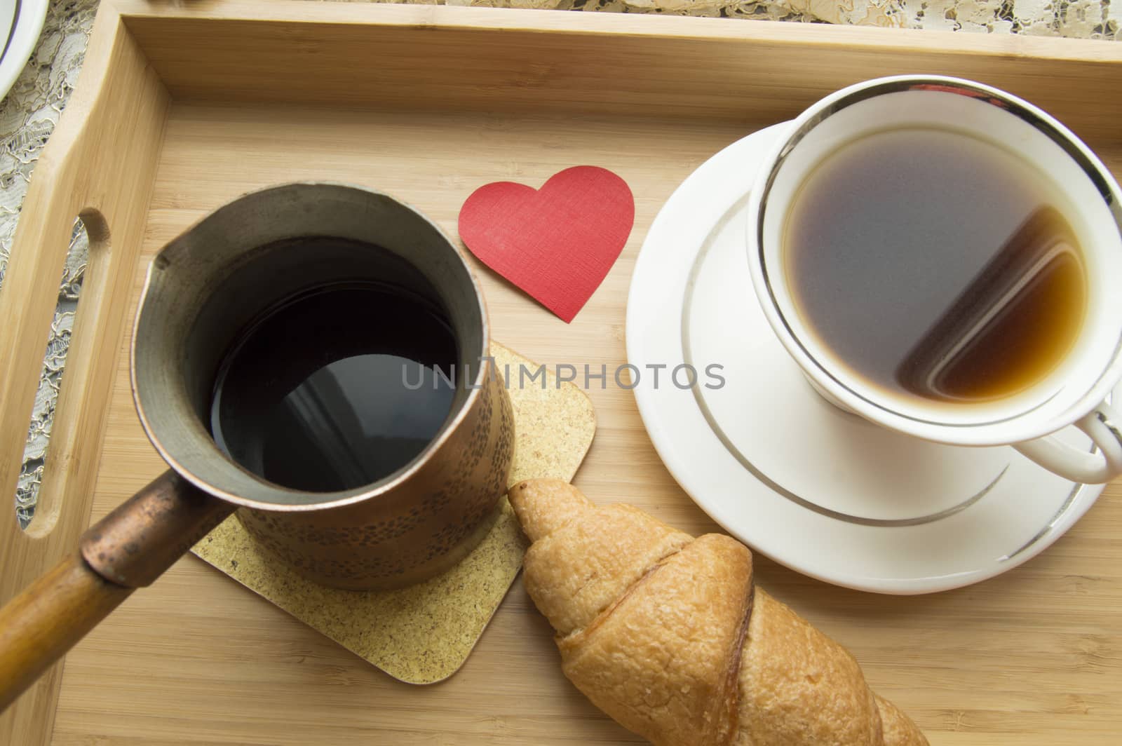 Breakfast Valentine's Day a croissant and coffee on wooden tray.