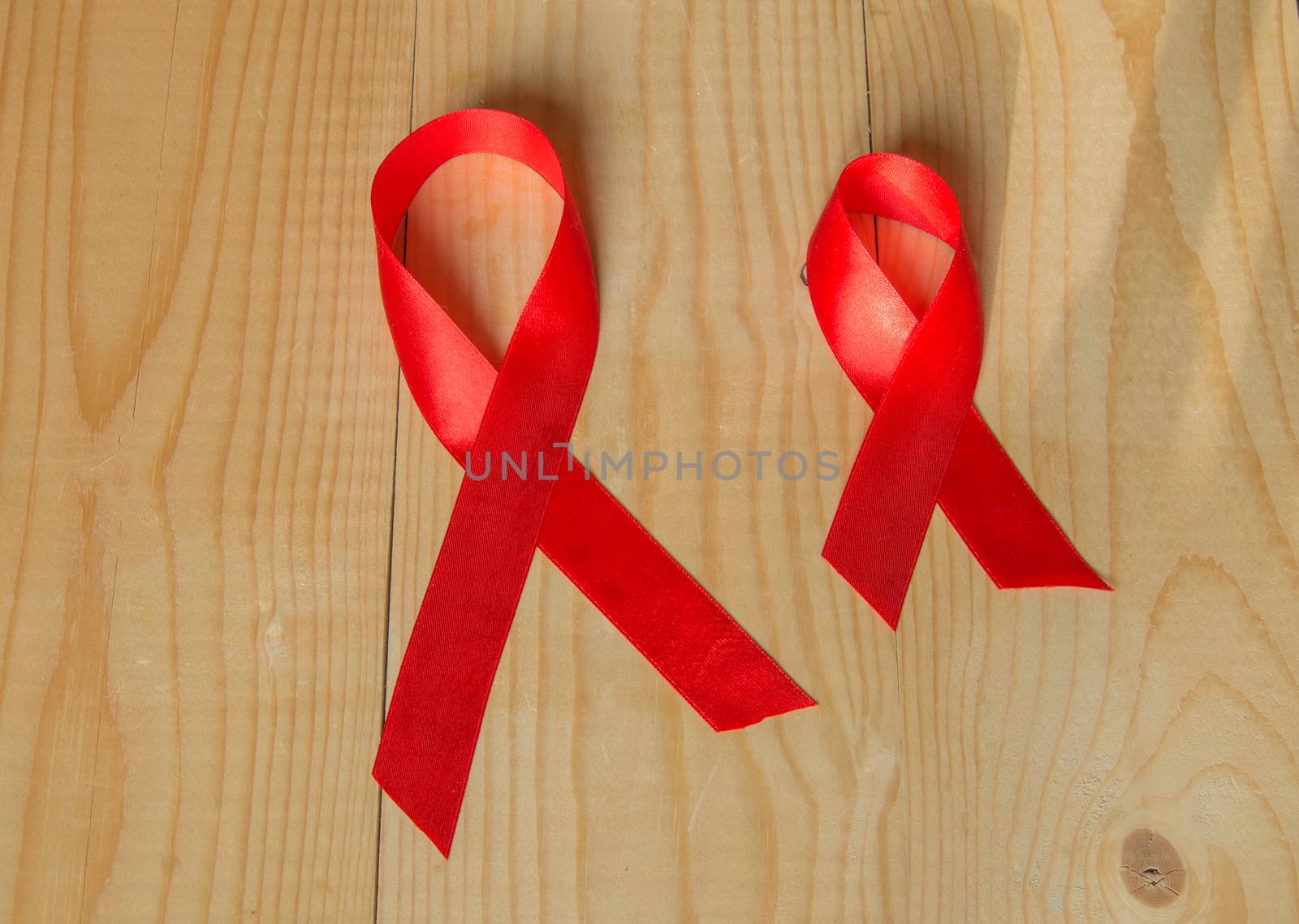 Awareness red ribbon on wood background: world day fight against AIDS, promotions to public support for the health of people living with HIV in December by claire_lucia