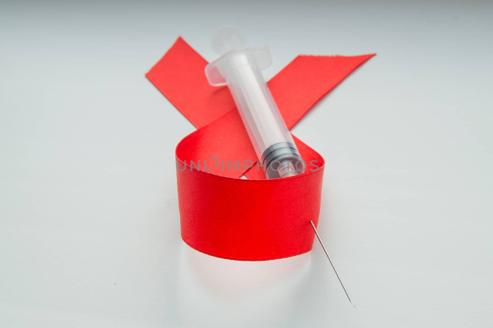 Awareness red ribbon and syringe on white background: world day against AIDS, the promotion of public support for the health people living with HIV in December by claire_lucia