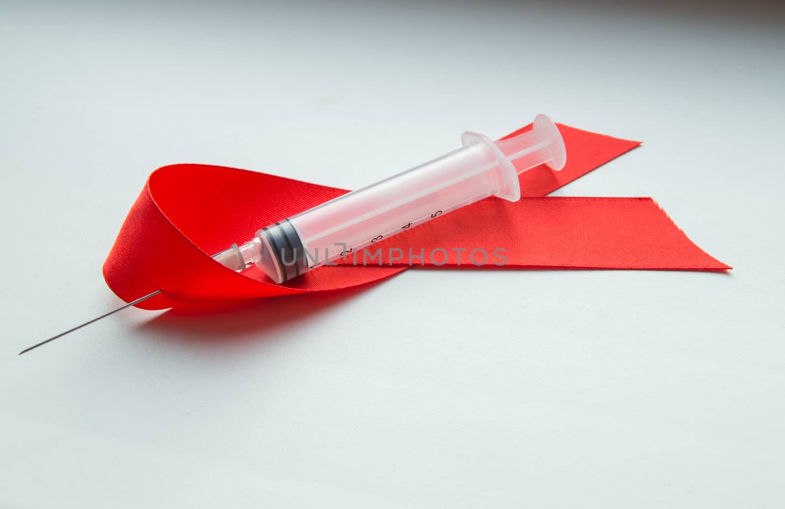 Awareness red ribbon and syringe on white background: world day against AIDS, the promotion of public support for the health people living with HIV in December by claire_lucia