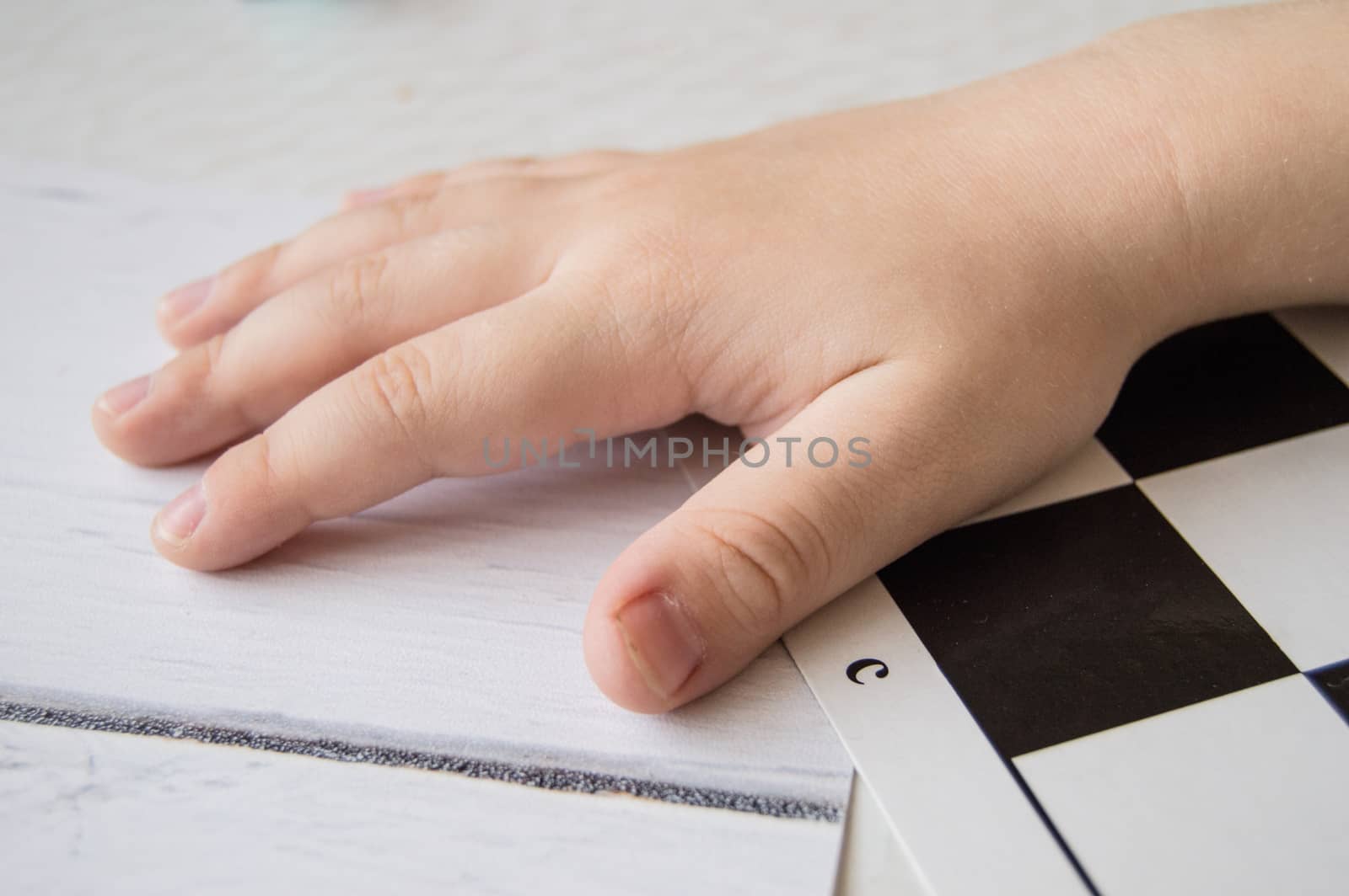 Close-up of a small child's hand lying on the chessboard, the concept of learning and intellectual development of children by claire_lucia