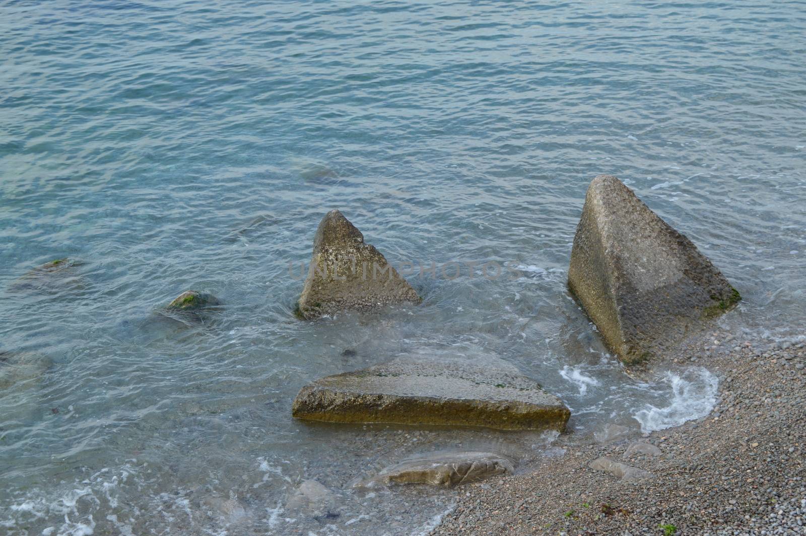 The waves of the sea beating on the huge boulders on the shore.