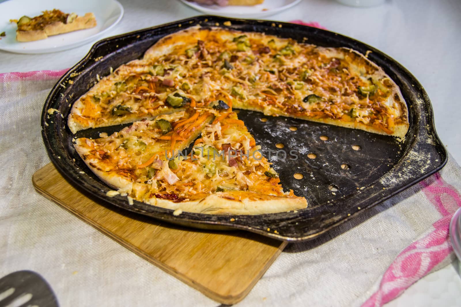 Freshly baked appetizing homemade pizza on a metal pan with cheese and ham, close-up selective focus by claire_lucia