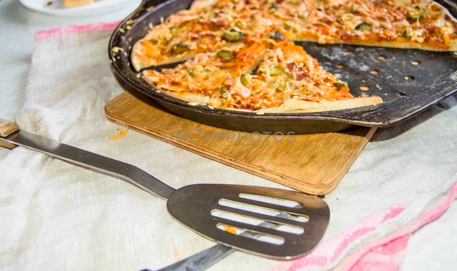 Freshly baked appetizing homemade pizza on a metal pan with cheese and ham, close-up selective focus by claire_lucia