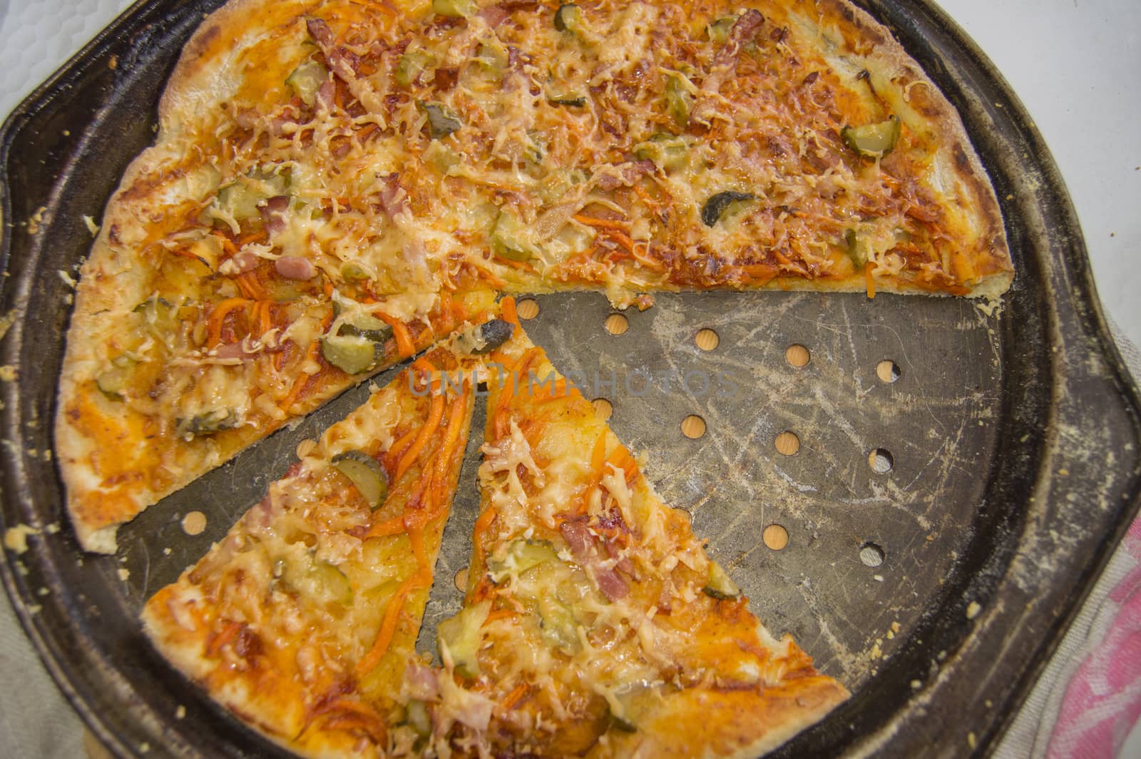 Top view of freshly baked appetizing homemade pizza on a metal pan with cheese and ham, close-up food background.