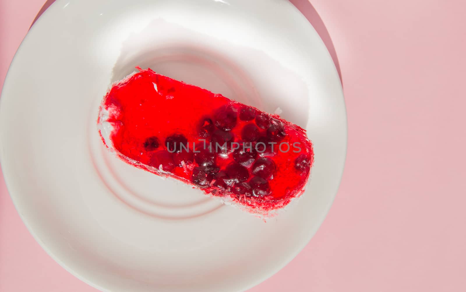Exquisite souffle cake with lingonberry jelly, with berry glaze and coconut on a white plate, top view close-up, pink background by claire_lucia