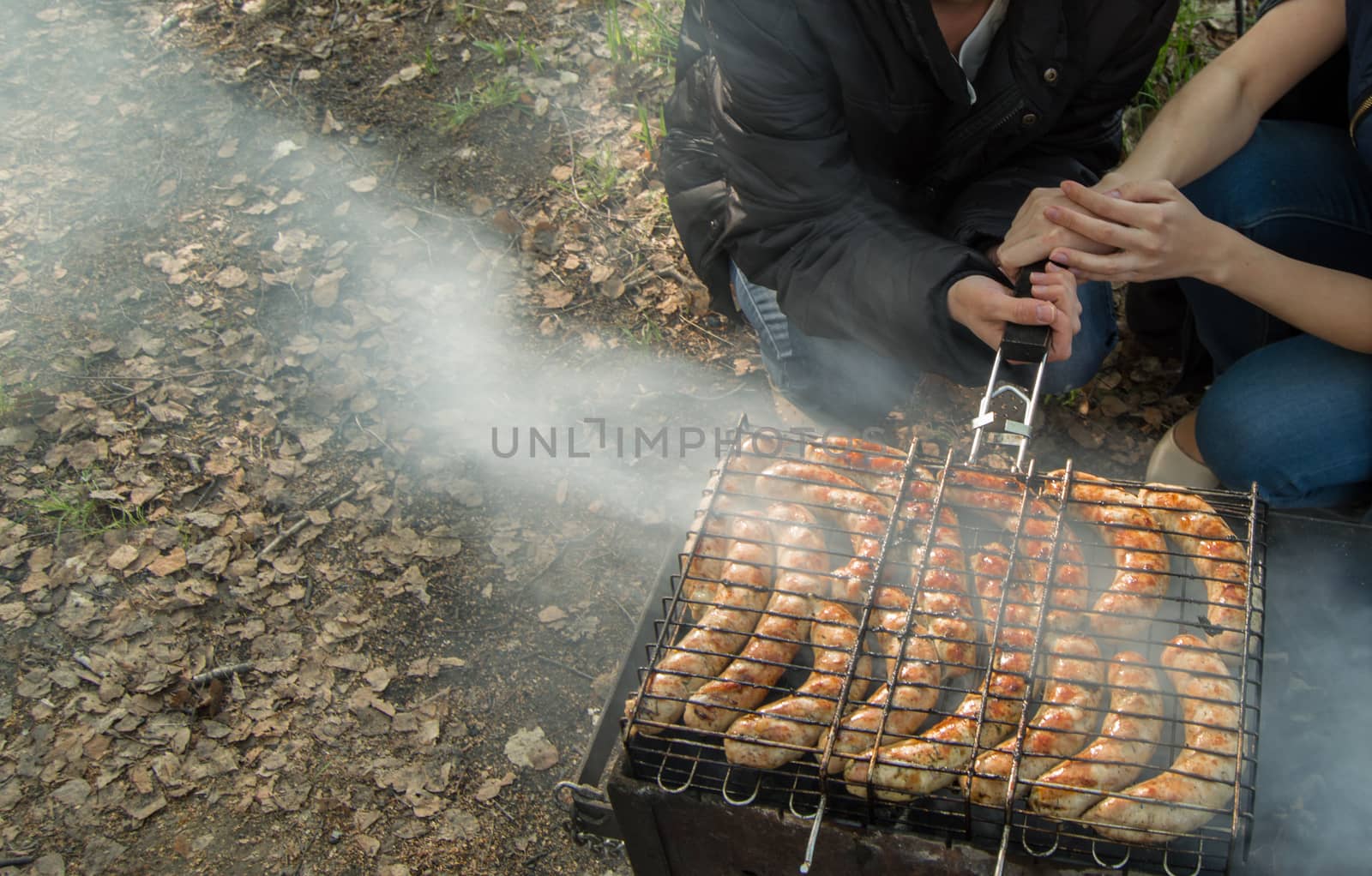 grilled sausages, two girls holding the grate over the fire, copy space.