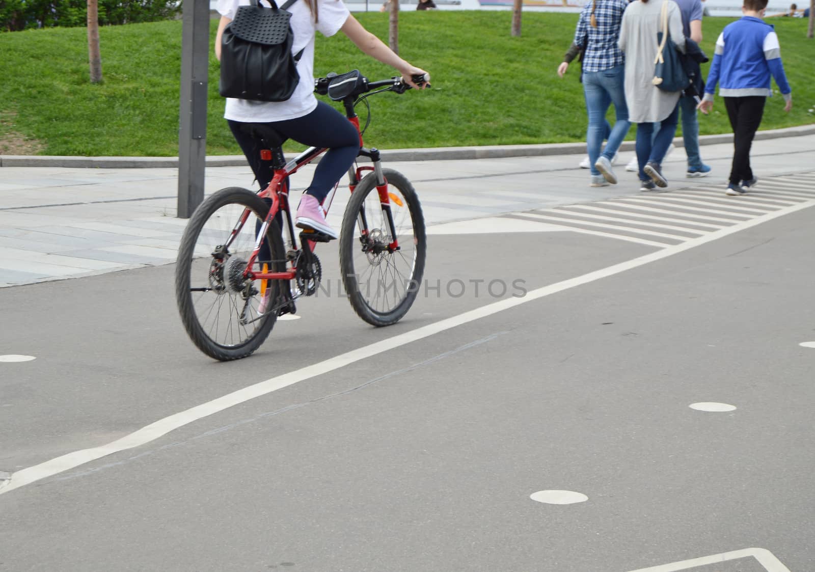 Girl on bike with backpack rides in the Park in the summer by claire_lucia