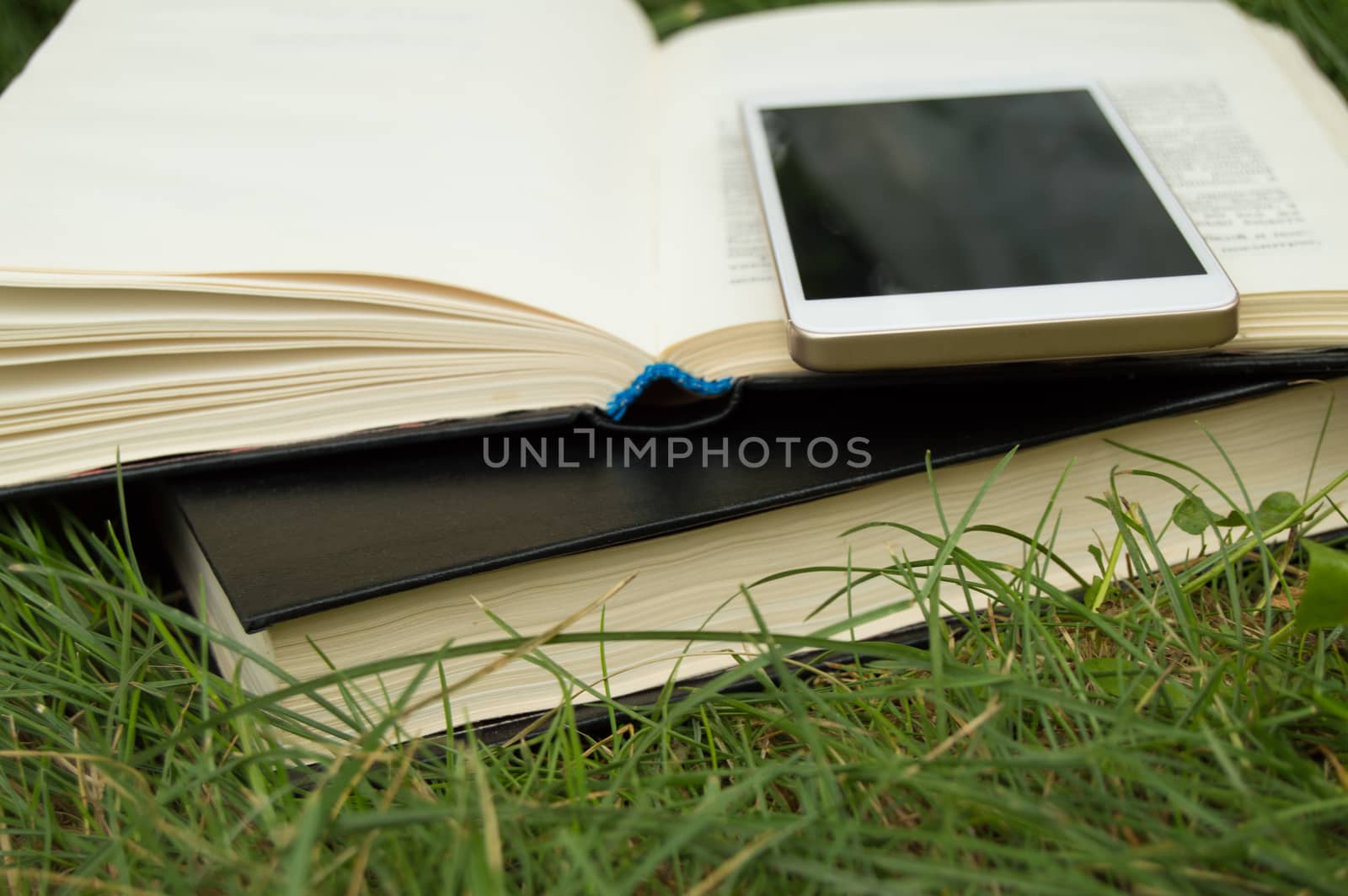 Books, smartphone on a green grass background, concept of education and training.