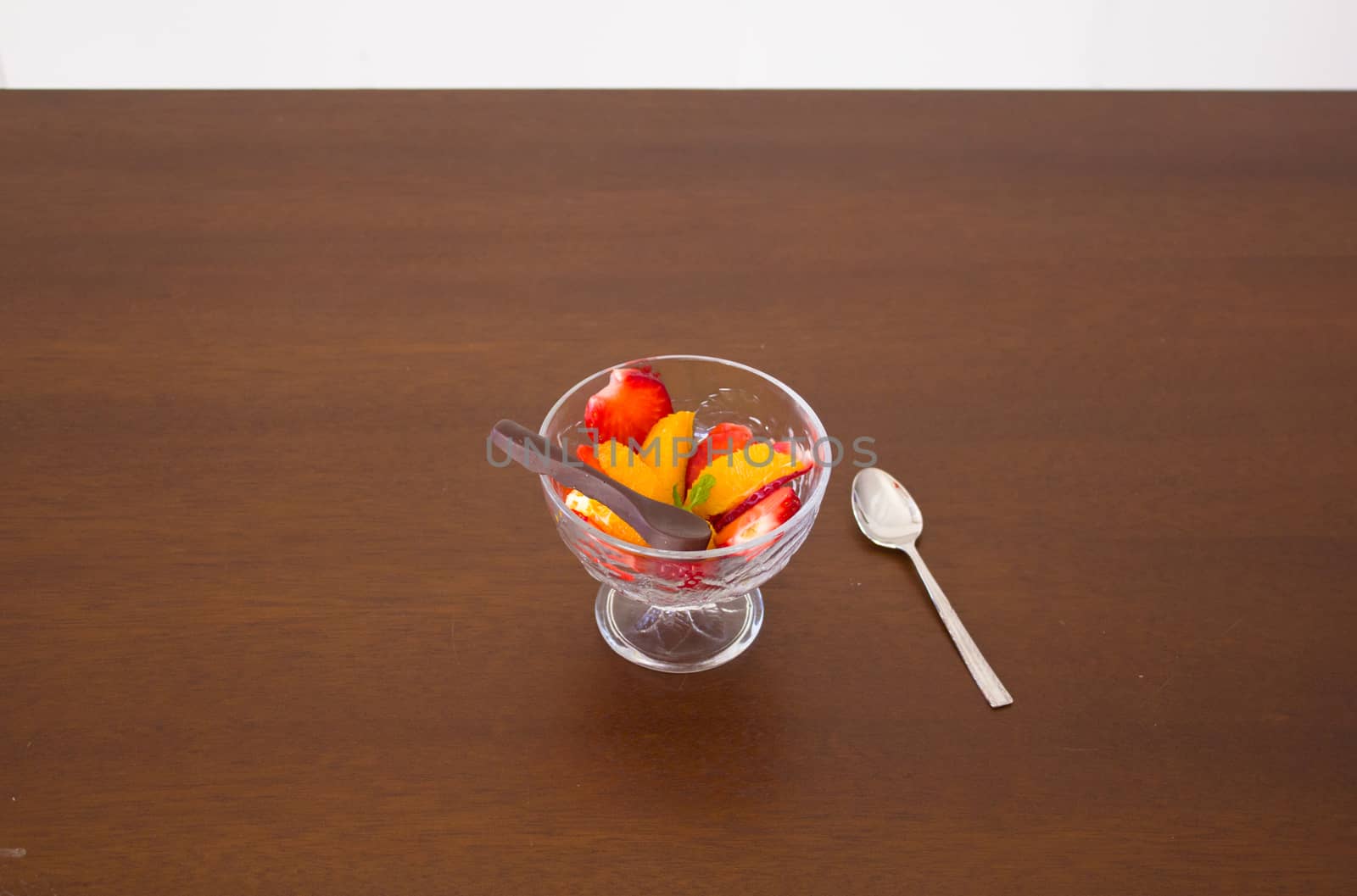 Salad fruit bowl with strawberries, orange and a chocolate spoon for dessert
