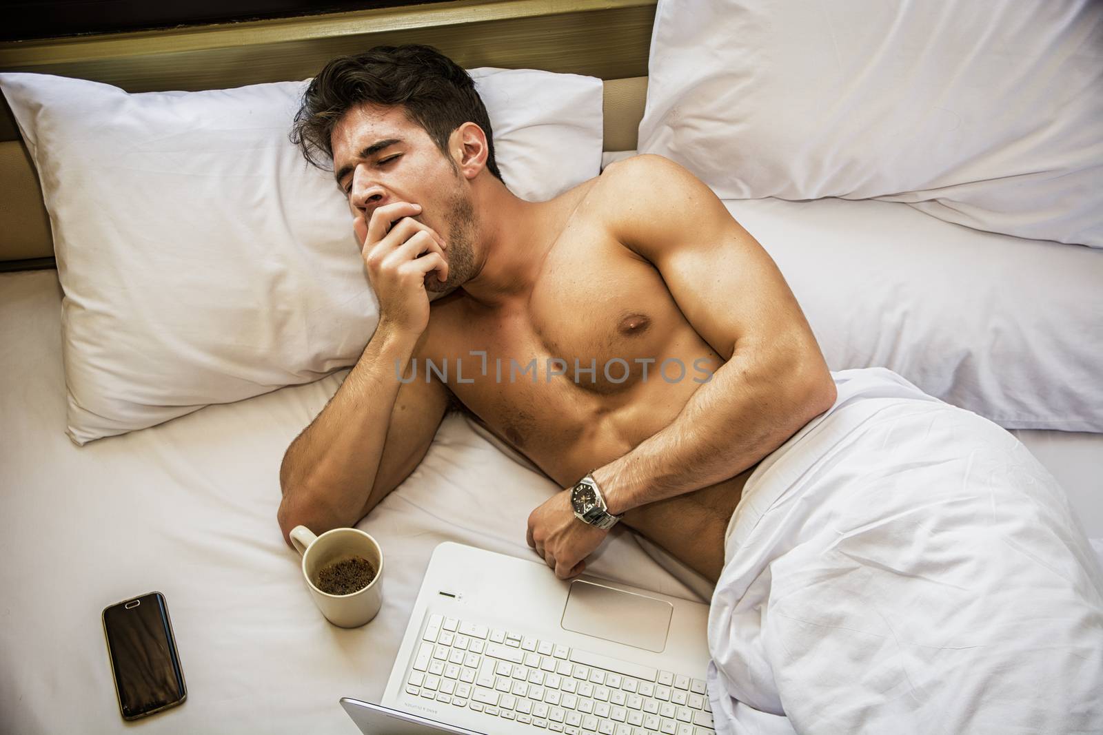 Young Handsome Shirtless Sleepy Man, Lying in Bed Yawning as He's Waking Up