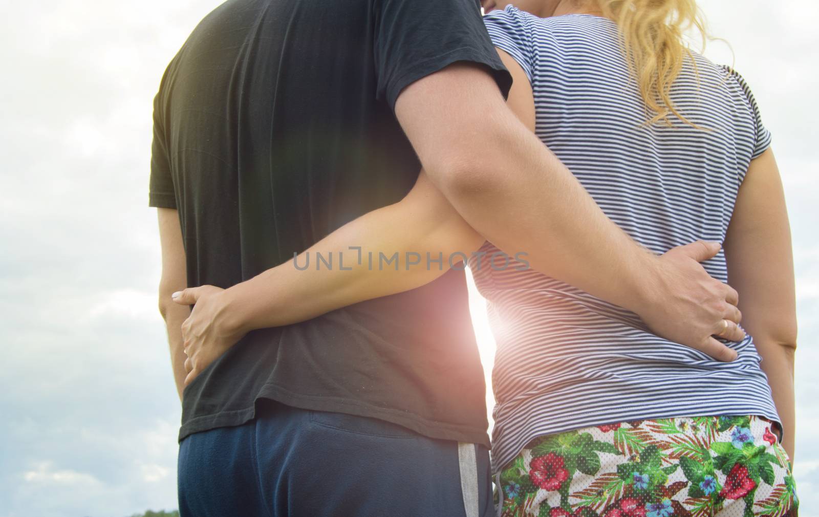 Young couple in love men and women hugging against the sky, Sunny summer day in the countryside in nature.