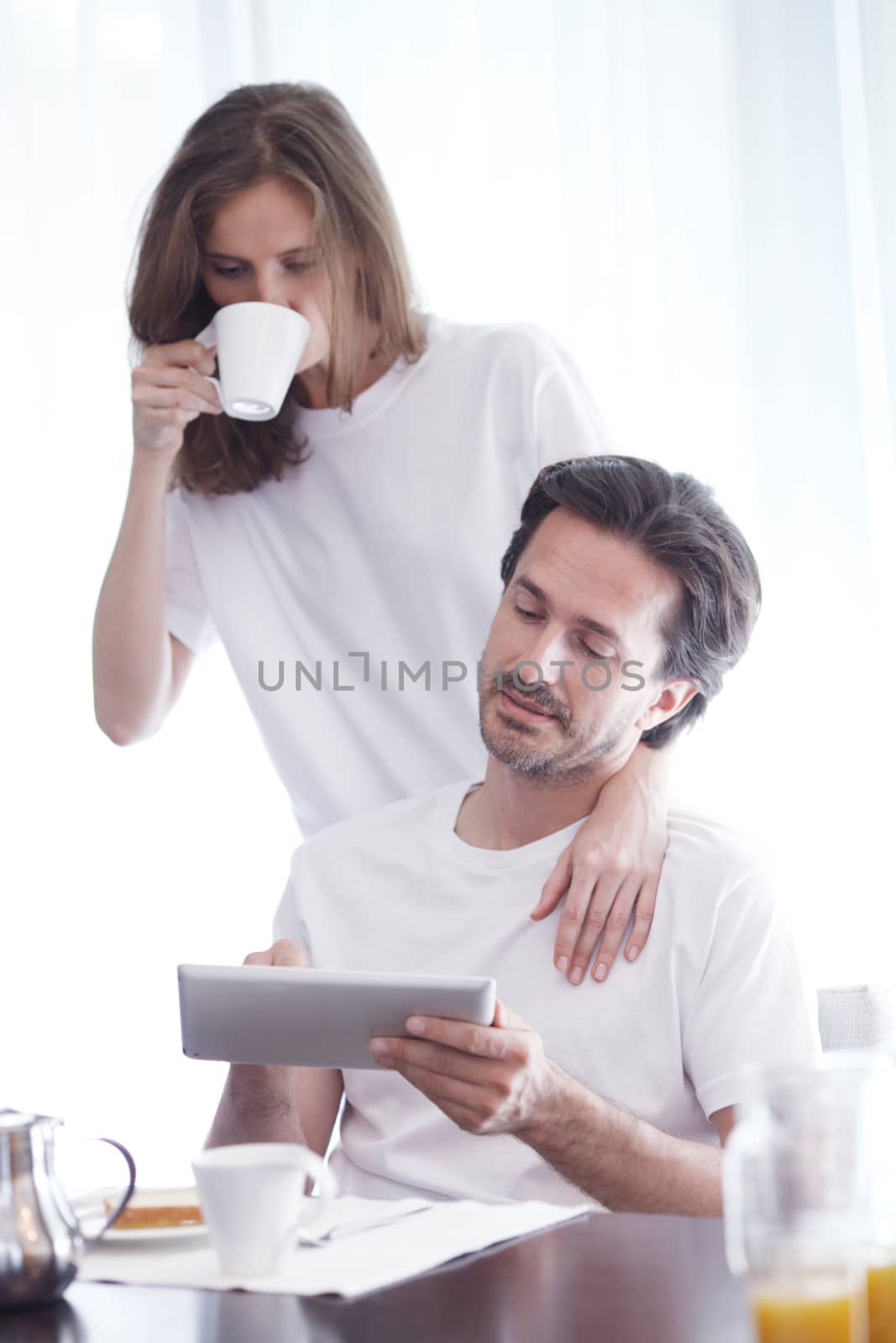 Couple using tablet during breakfast by ALotOfPeople