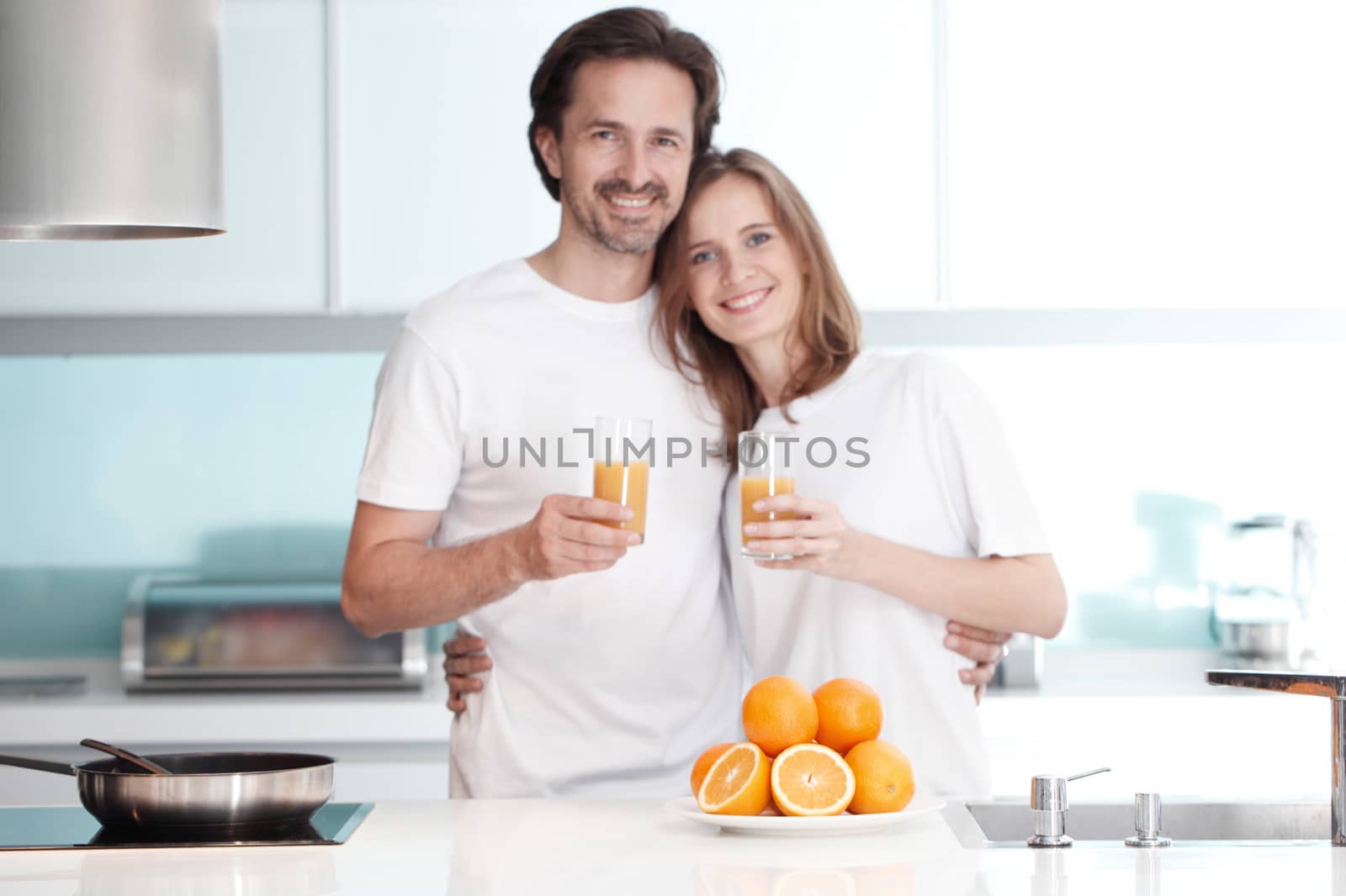 Couple with juice in the kitchen by ALotOfPeople