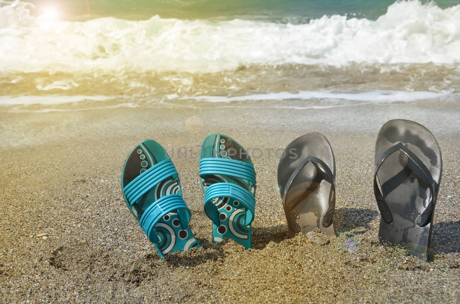 Two pairs of flip-flops on the beach, tropical holiday concept, sunlight by claire_lucia
