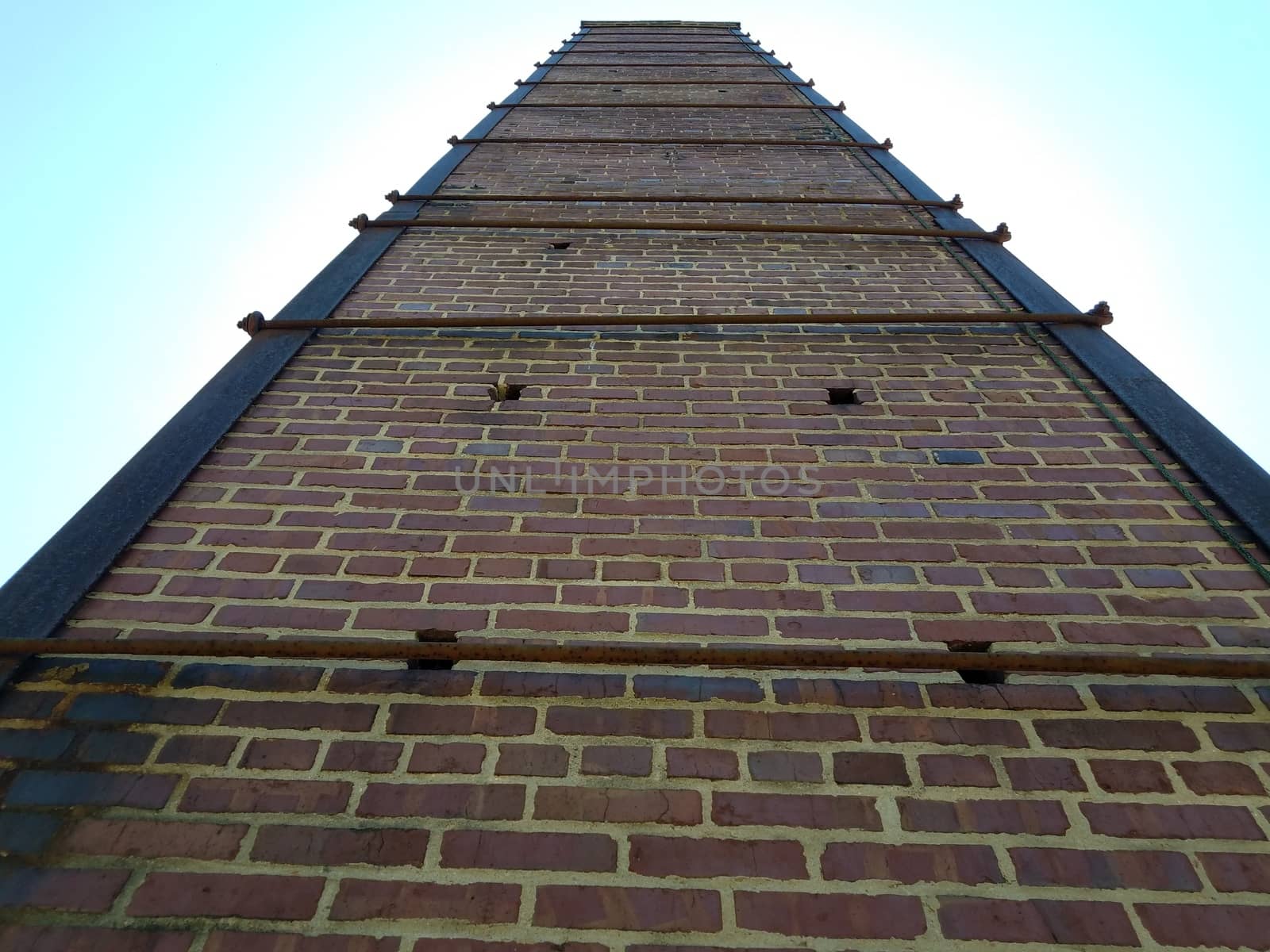 tall red brick chimney or masonry with metal support rods