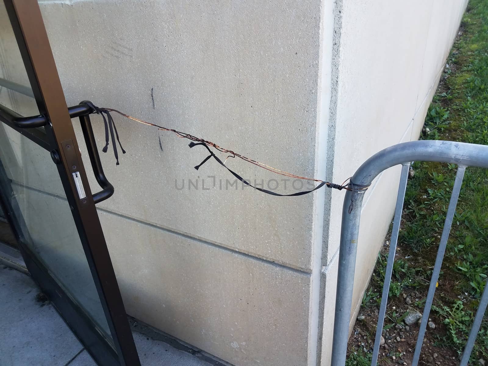 metal wire and string holding door open with metal fence and cement wall