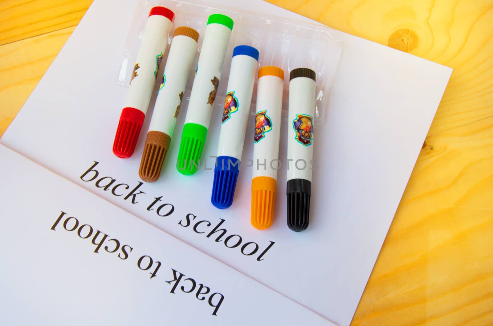 Back to school. Sheet of paper with text and colored markers on a wooden background, top view.