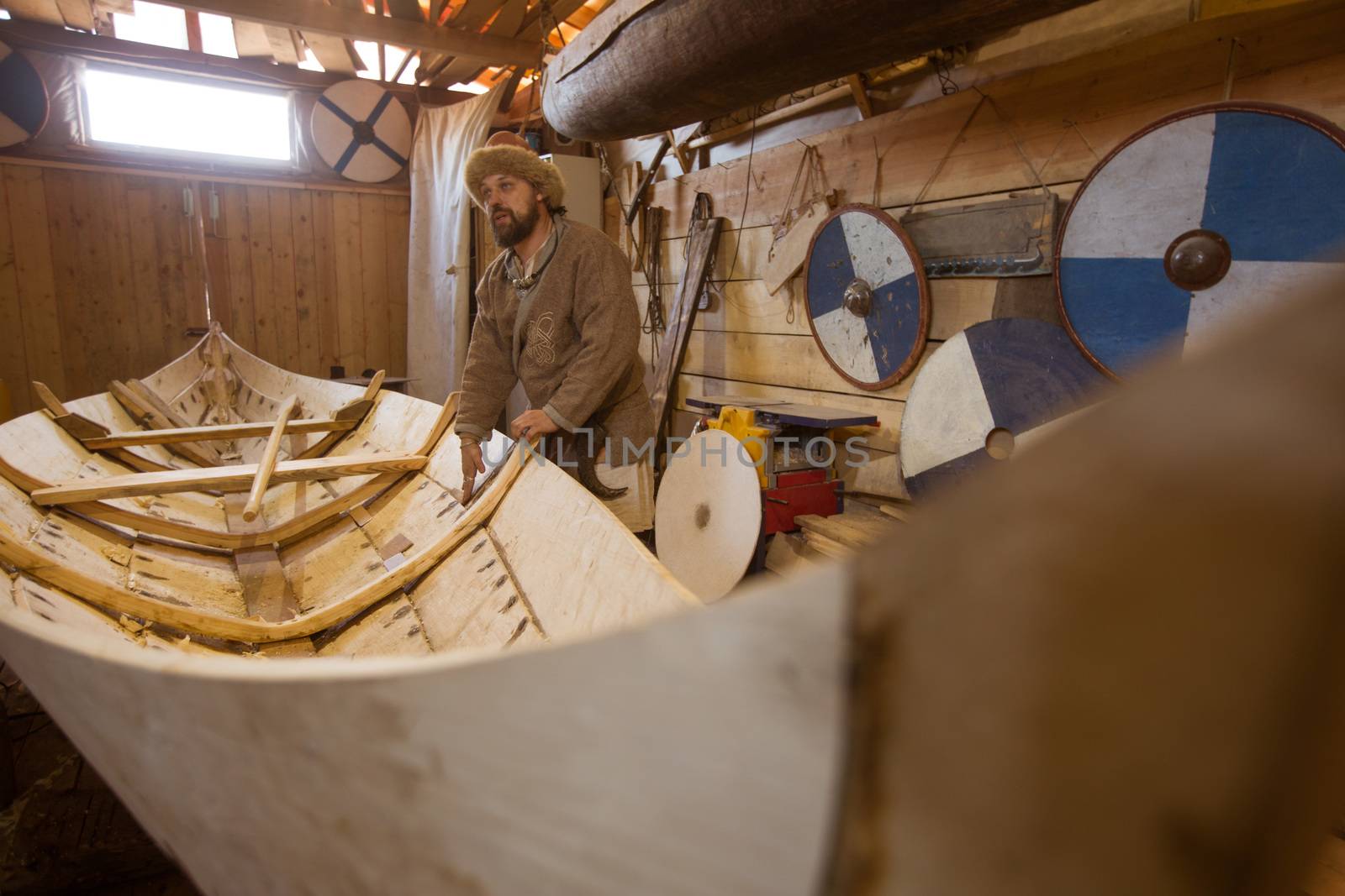 Handmade wooden boat in the barn and reenactor in medieval clothes