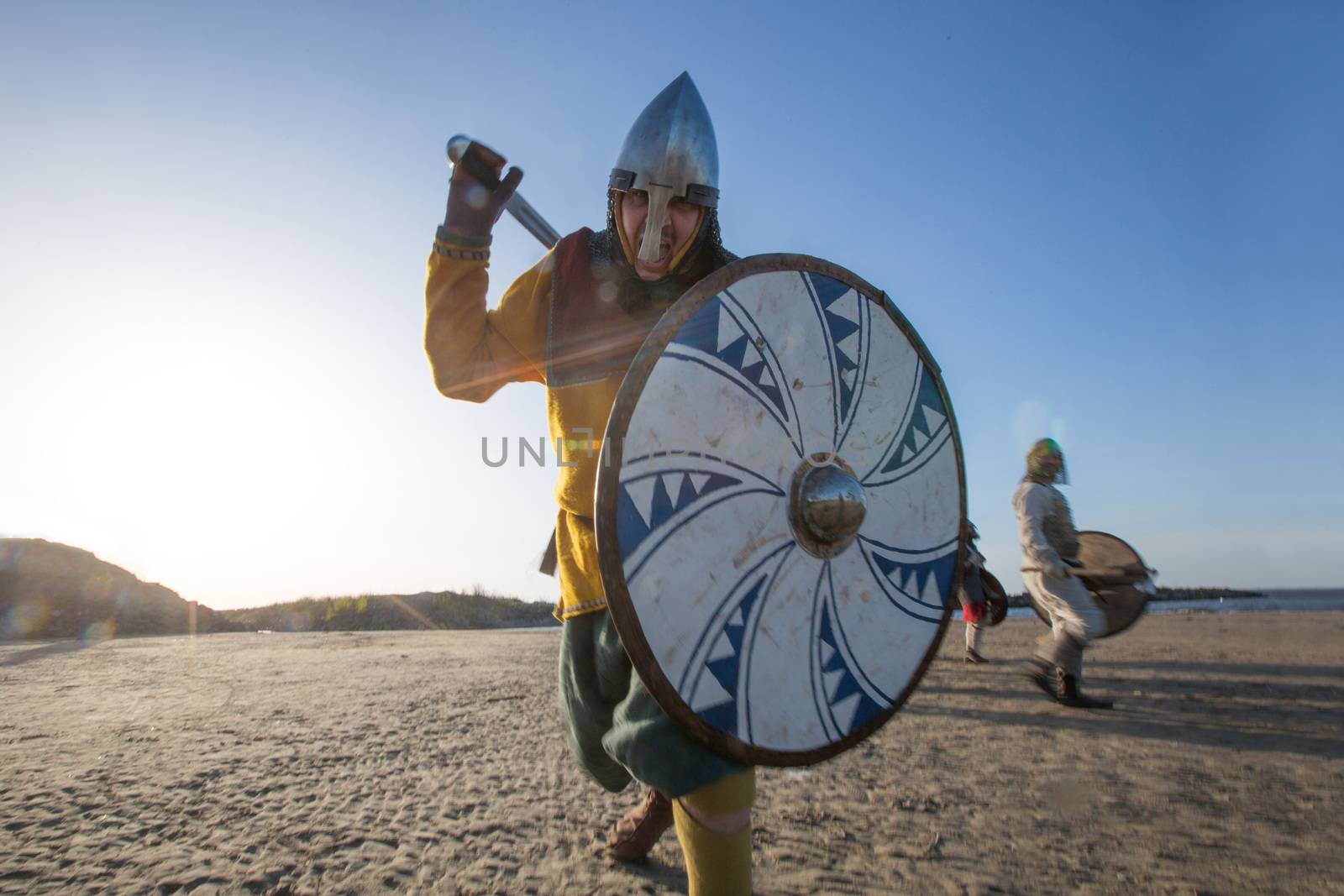 Slavic warrior reenactor with axe and shield training outdoors at seaside , running at camera