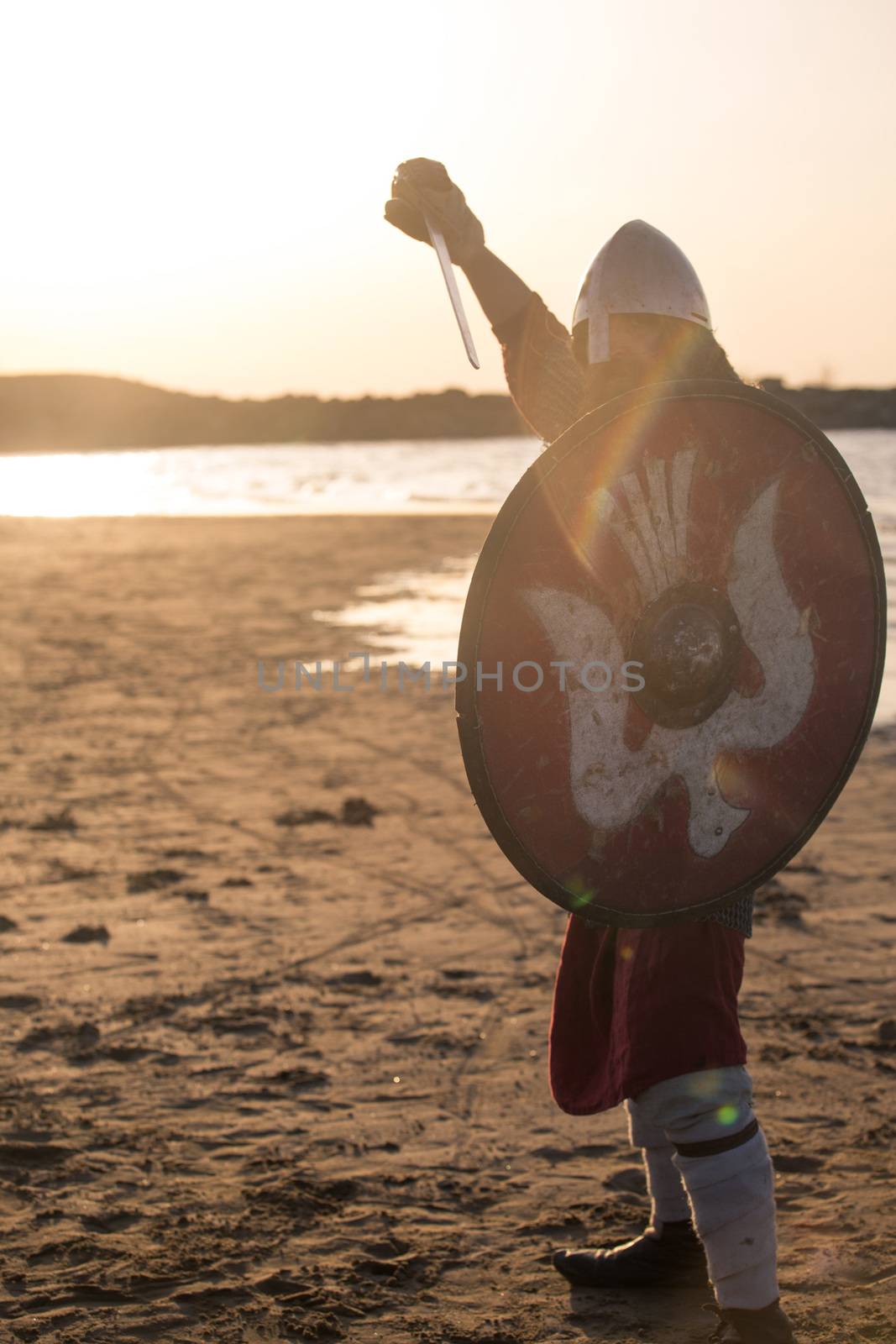 Portrait of slavic warrior reenactor with sword and shield posing outdoors at seaside