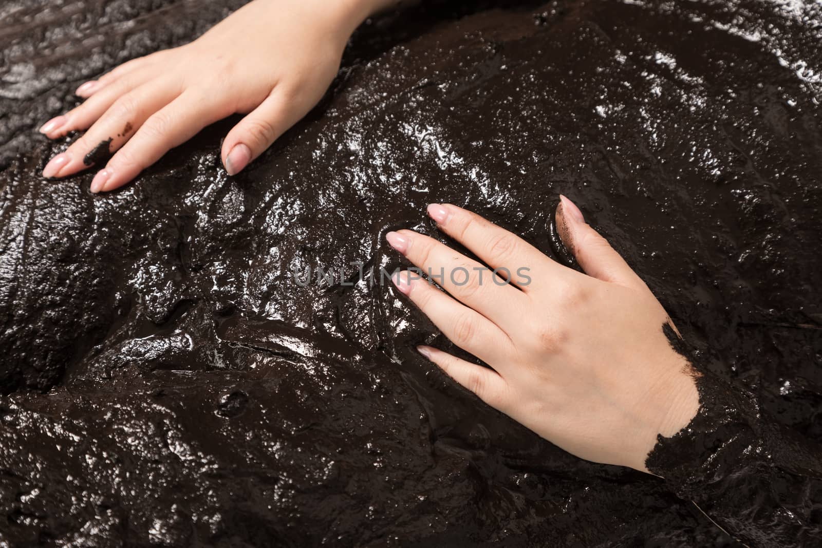 The female hand lies on black therapeutic mud