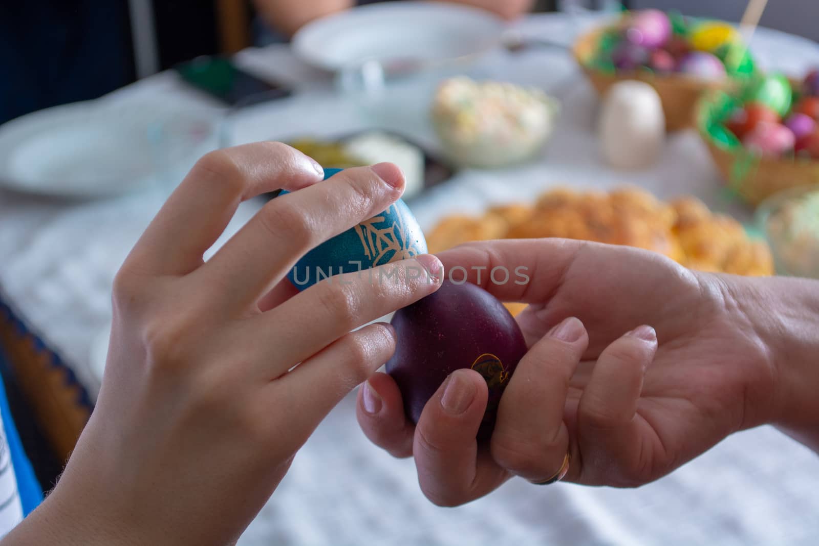 Knocking eggs on ortodox easter with table full of food in the background