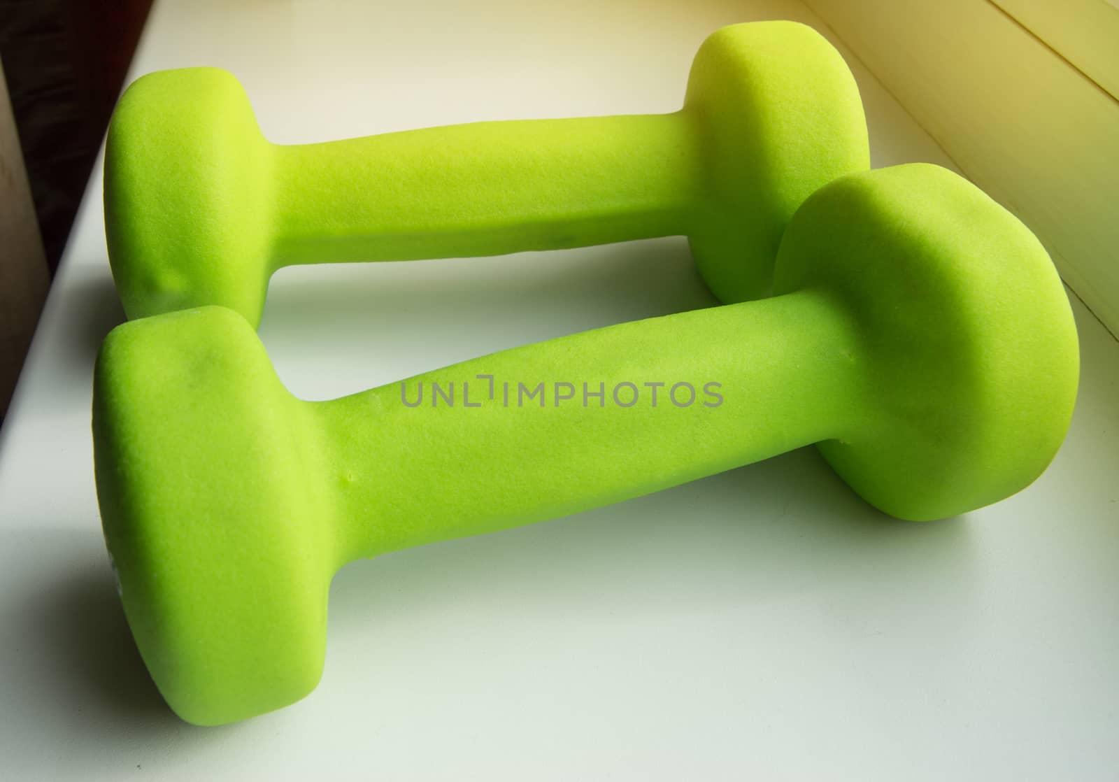 Concept of fitness, healthy lifestyle-two green dumbbells for sports, sunlight.