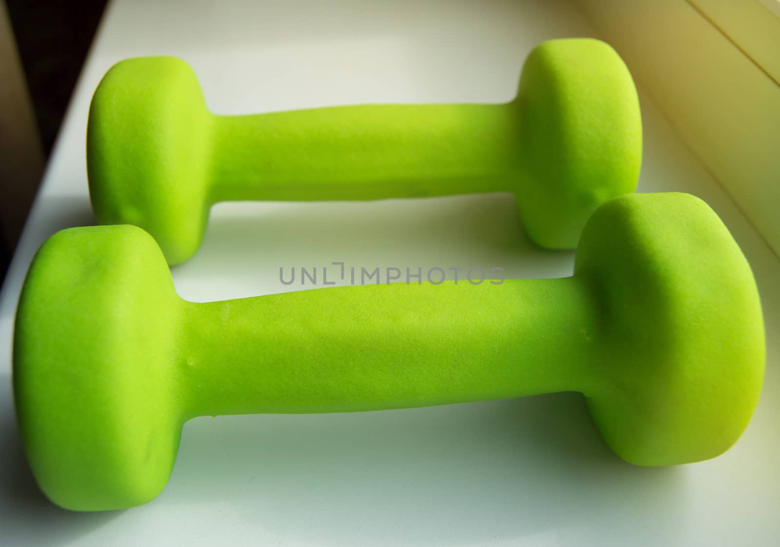 Concept of fitness, healthy lifestyle-two green dumbbells for sports, sunlight by claire_lucia