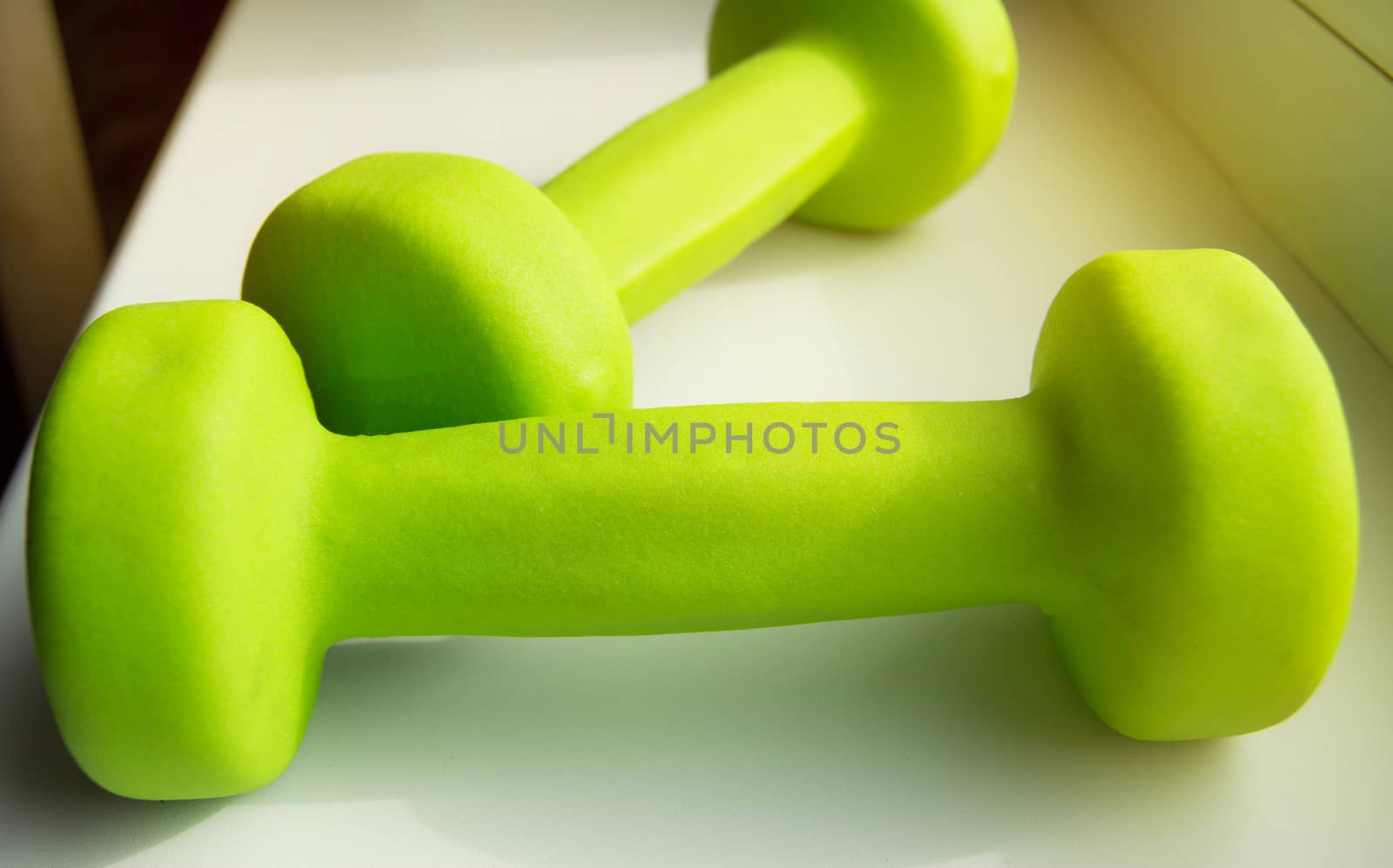 Concept of fitness, healthy lifestyle-two green dumbbells for sports, sunlight.