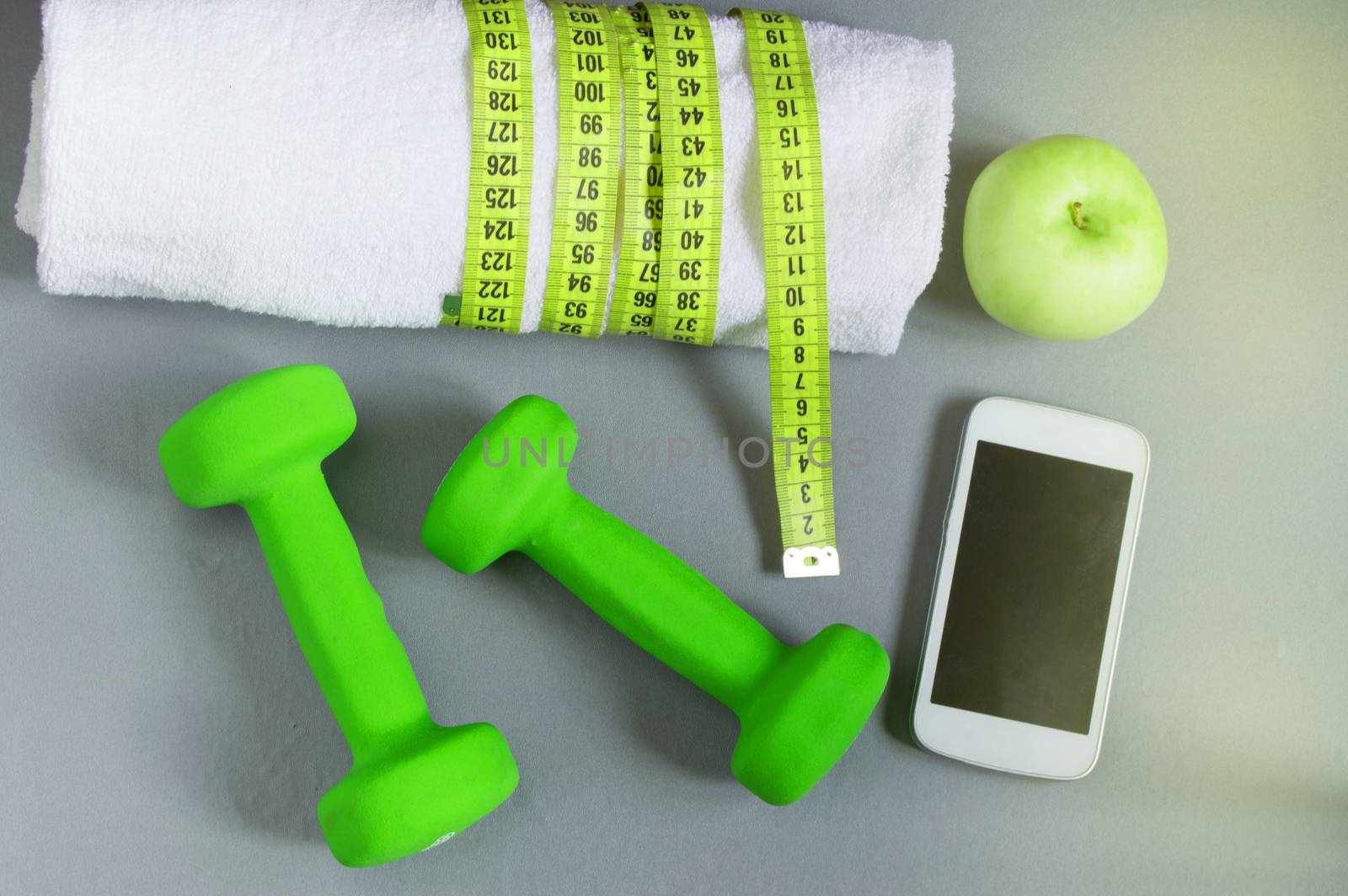 Fitness concept, dumbbell, mobile and a towel and measuring tape, top view.