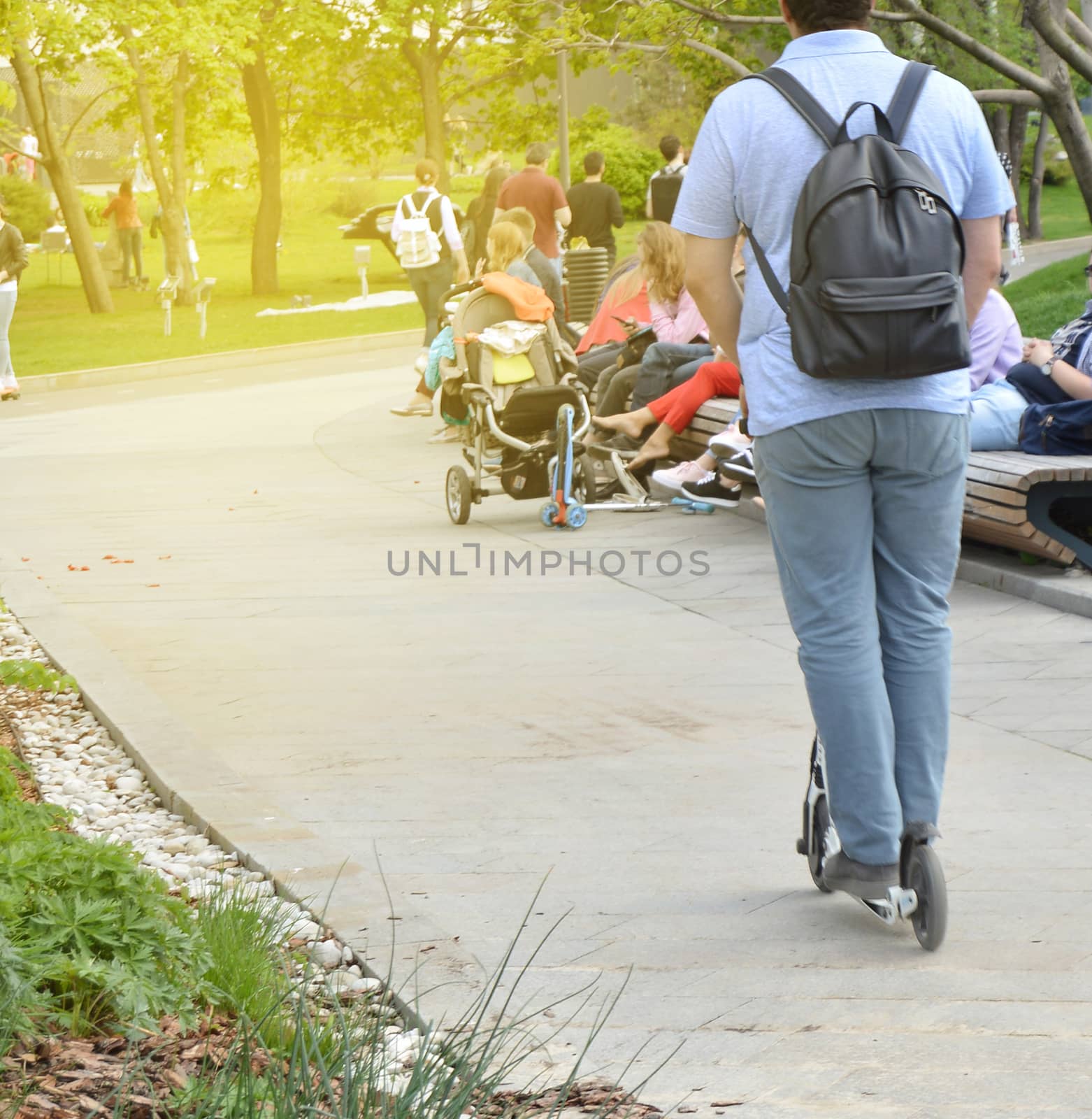 Confident tall man rides a scooter through the Park in the weekends in summer