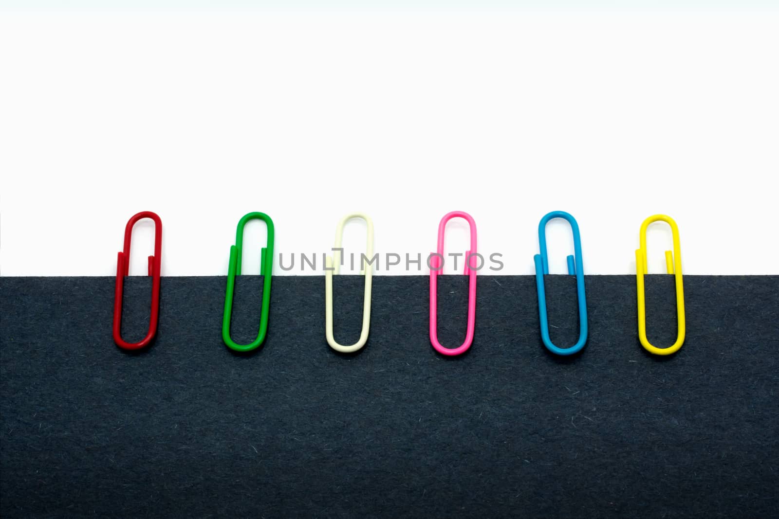 Paperclips of Various Color Lined Up along the Edge of a Paper by seika_chujo