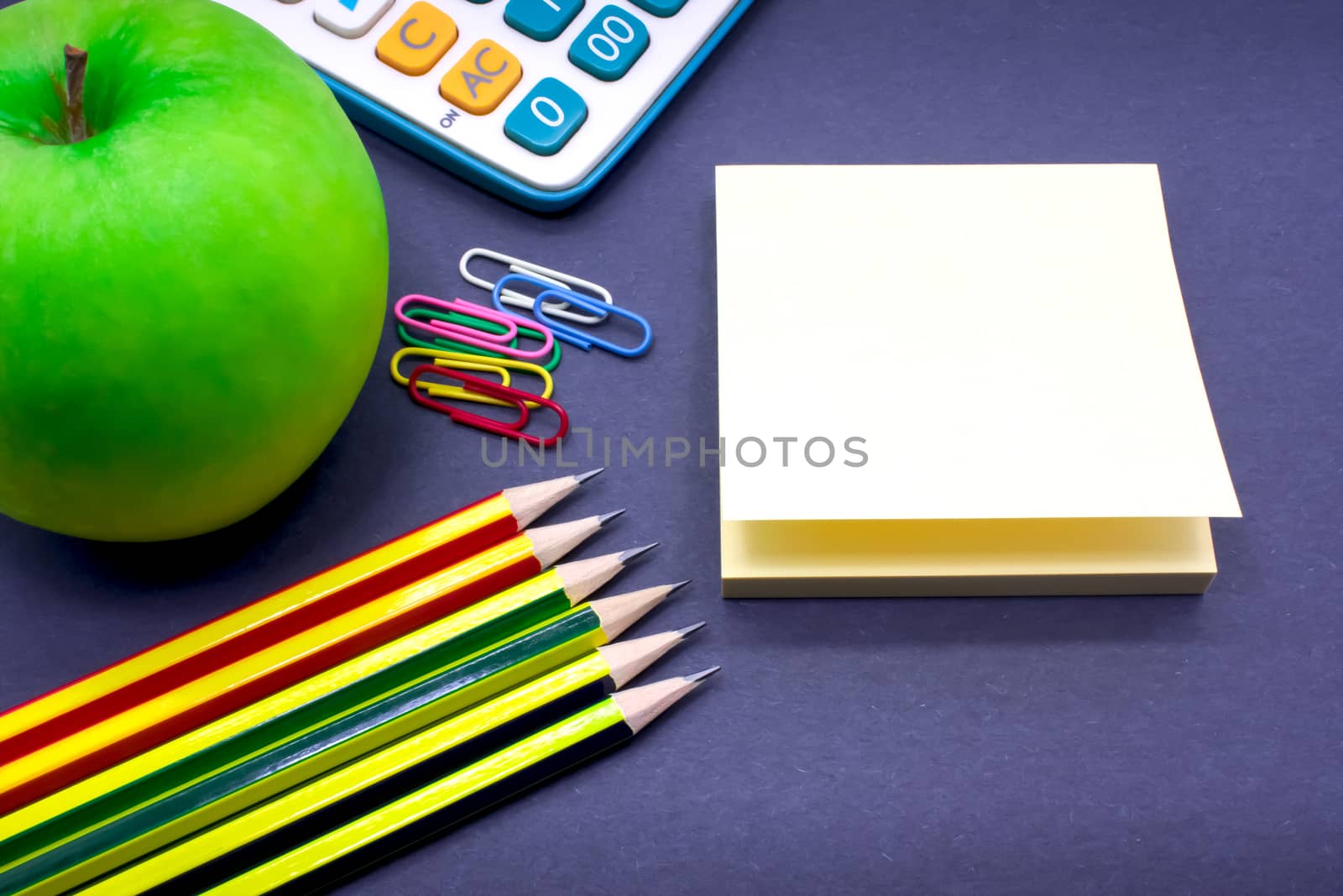 Assorted Stationary with a Green Apple on the Desk