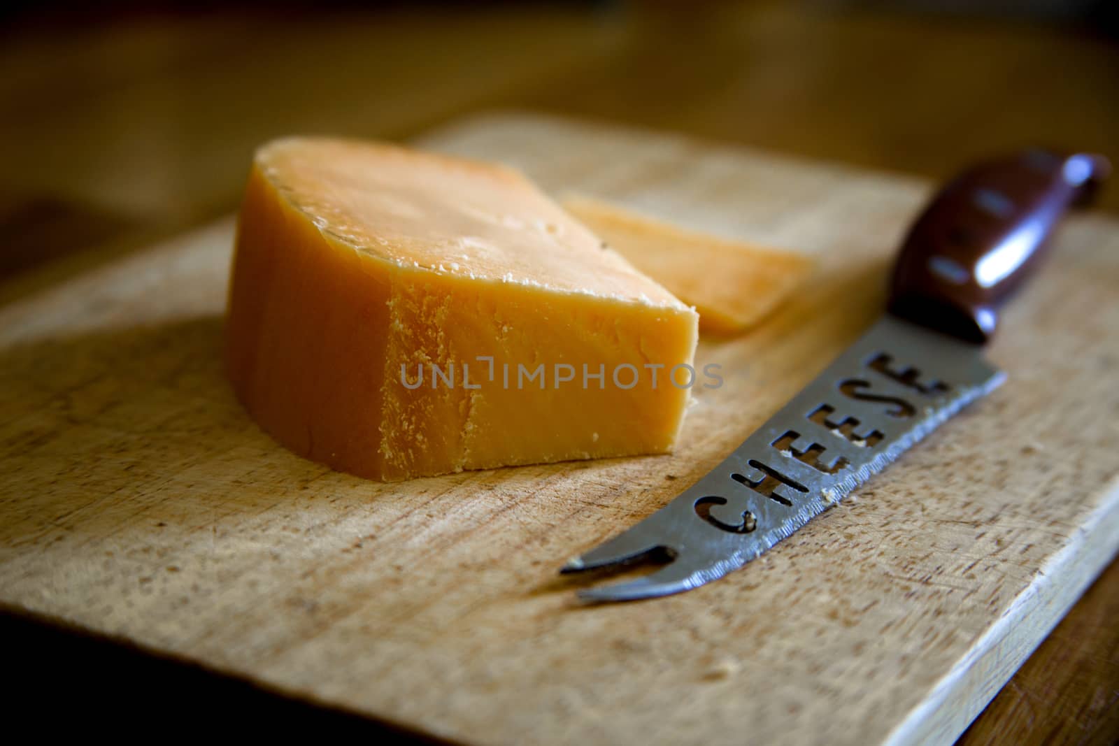 Parmesan cheese with knife on cutting board on wooden background by Anelik