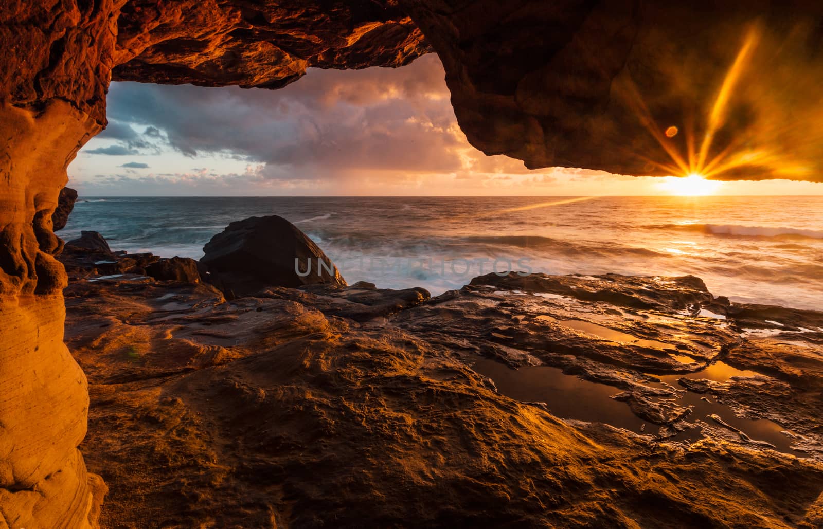 Coastal rock tunnels to cliff ledges with early morning sunlight by lovleah