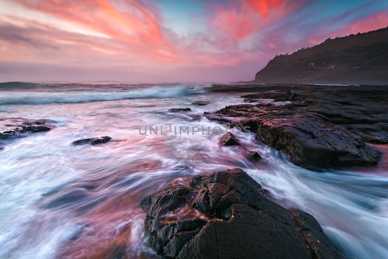 Collossal waves wash onto the coast while an impressive clouds dance in the sky changing shape and form dramatically, both clouds and water competing for attention drawing the viewer in with an epic display of magnificent colours and texture