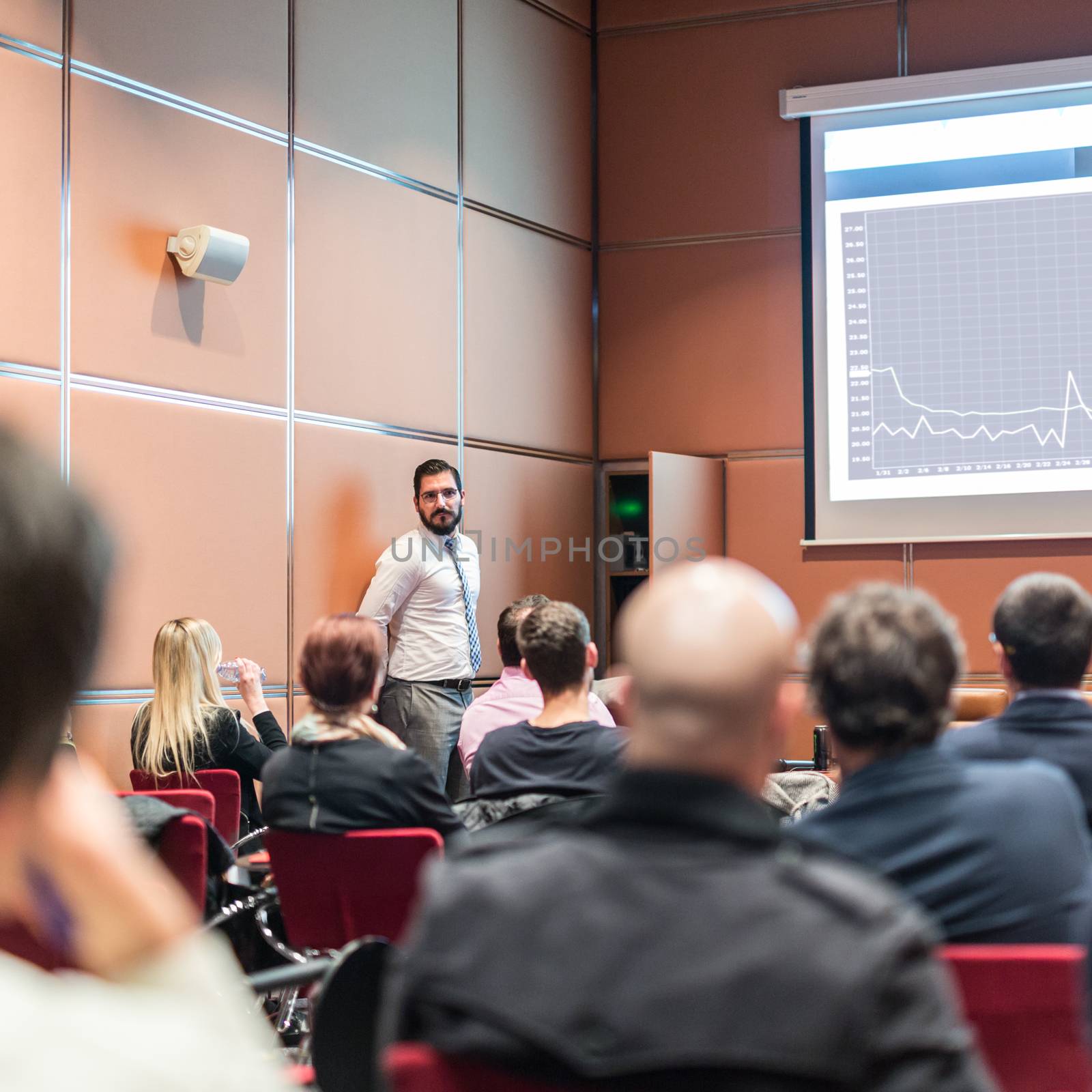 Public Speaker Giving a Talk at Business Meeting. Audience in the conference hall. Skilled coach answers questions of participants of business training. Business and Entrepreneurship concept.