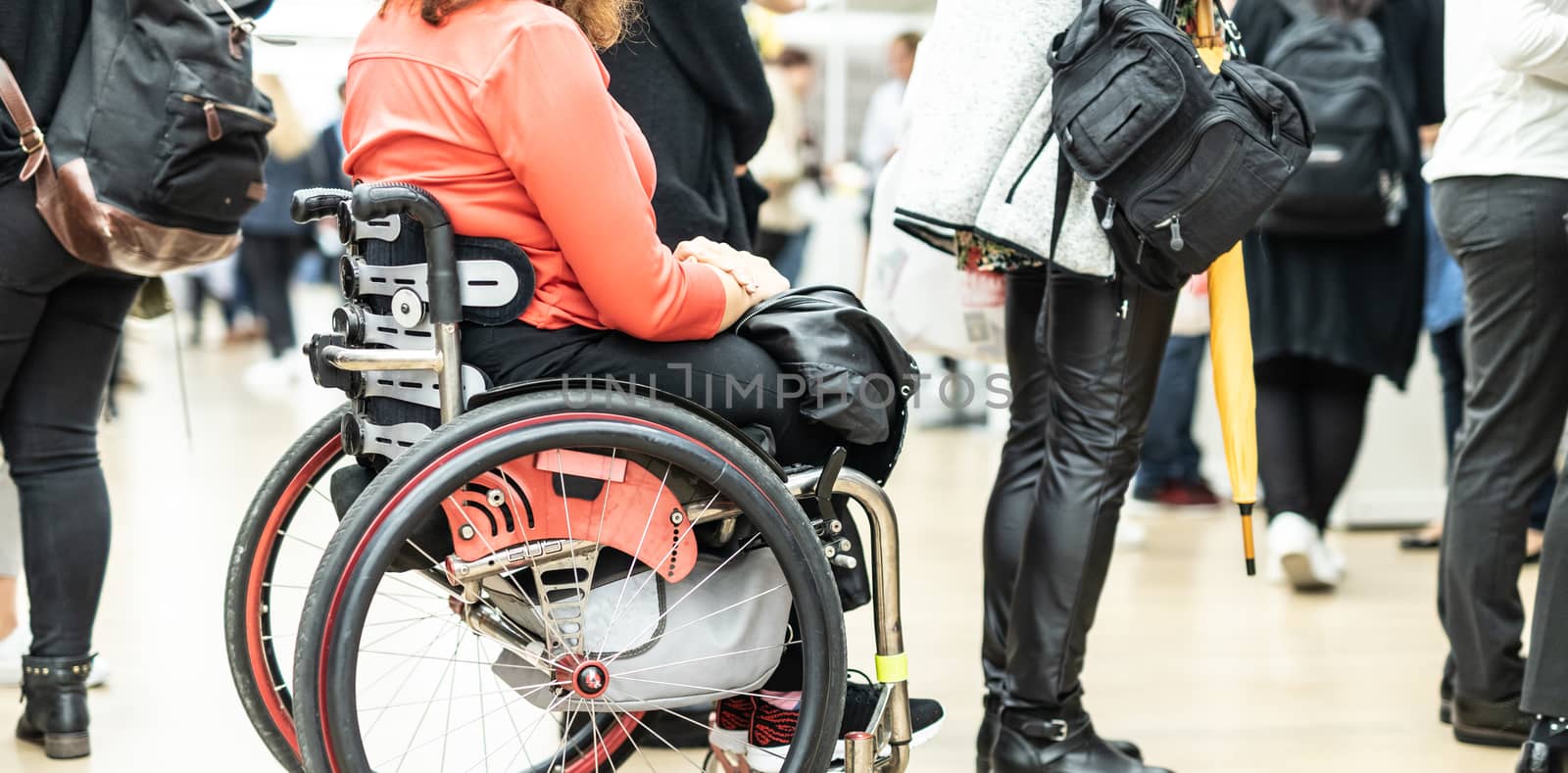 Close up of unrecognizable hanicapped woman on a wheelchair queuing in line to perform everyday tasks. by kasto