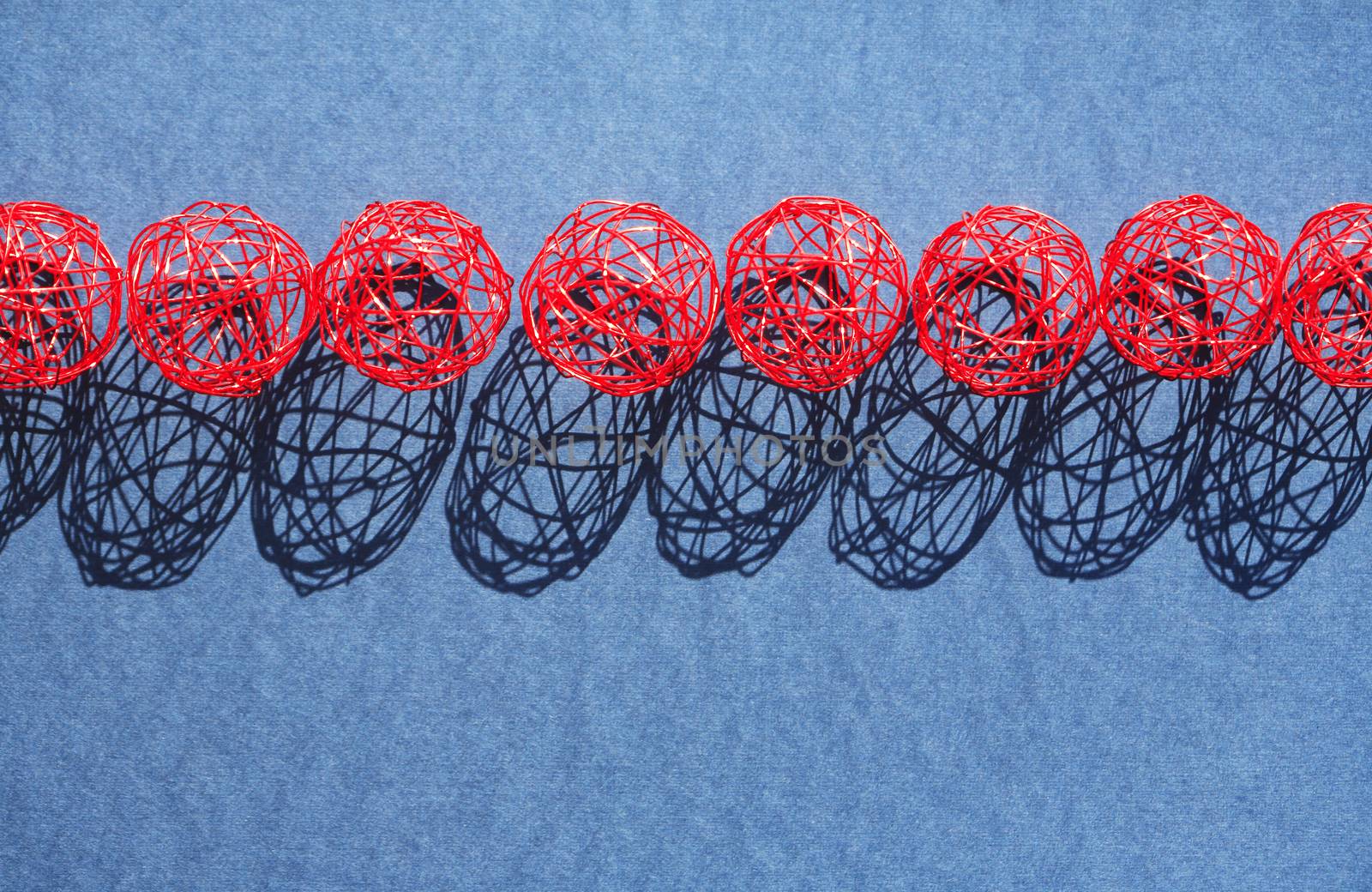 Set of red balls made from wire in a row against sun light