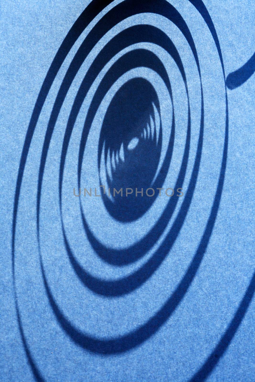 Industrial concept. Closeup of shadow of spiral on blue background