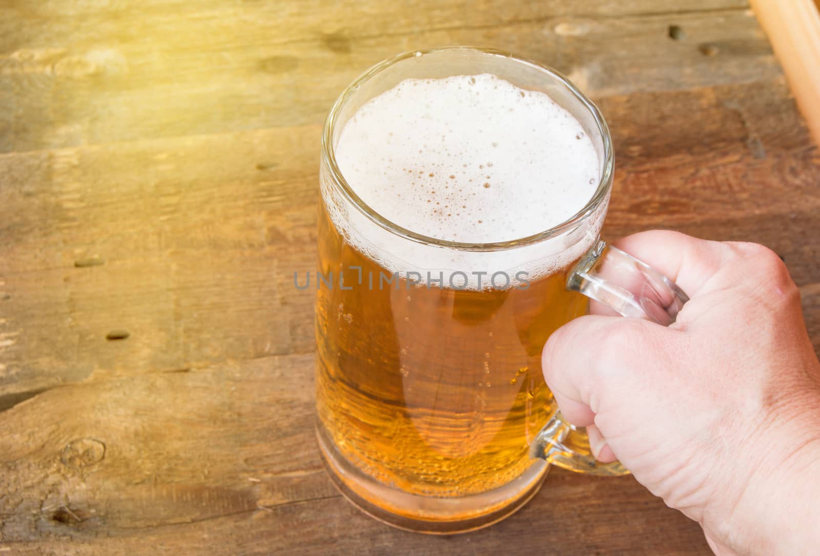 Summer, party, Glass mug of beer standing on an old wooden background, female hand holds.