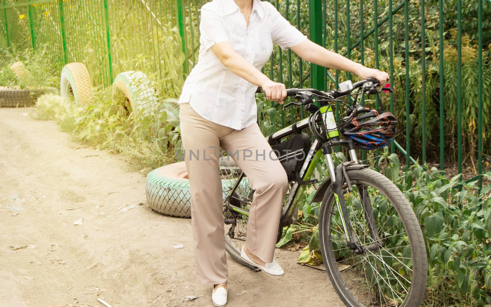 Summer, family, happy young woman on a Bicycle standing on the road near the fence of the Park by claire_lucia