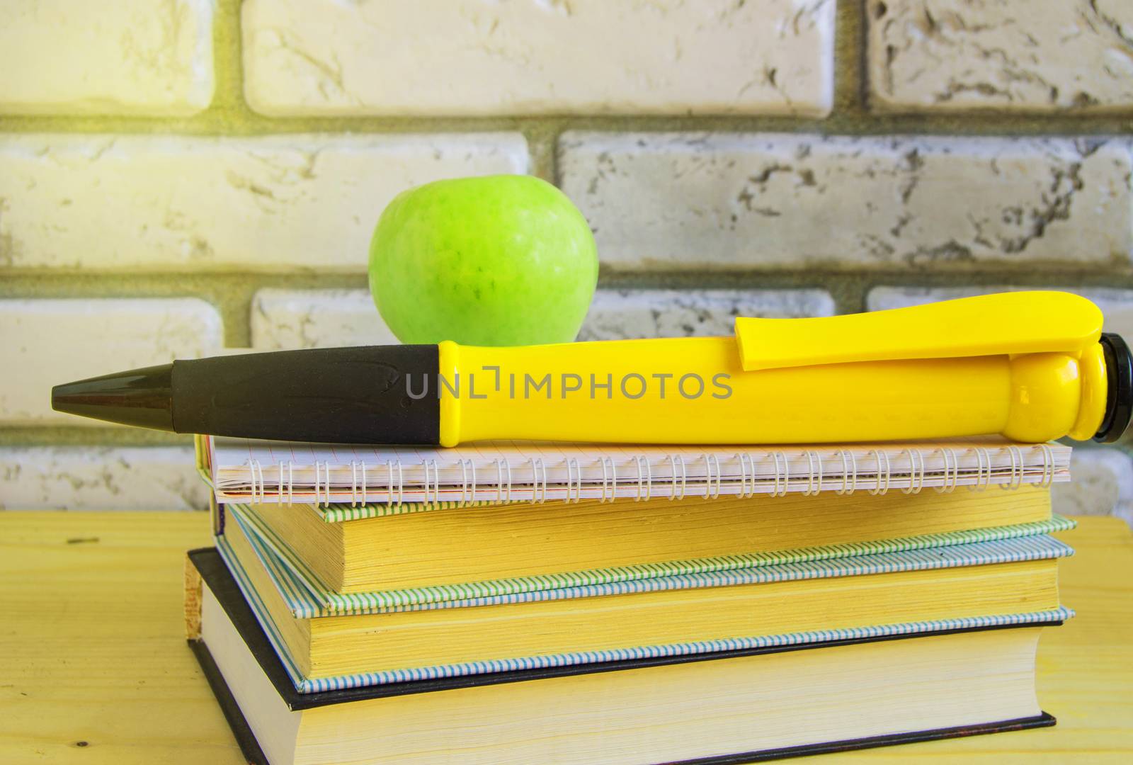 Teacher's Day concept and back to school, green Apple, large souvenir pen on books and notebooks, sunlight by claire_lucia