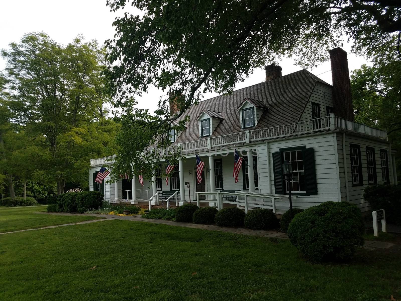 house with deck and flags of the United States and green bushes and lawn