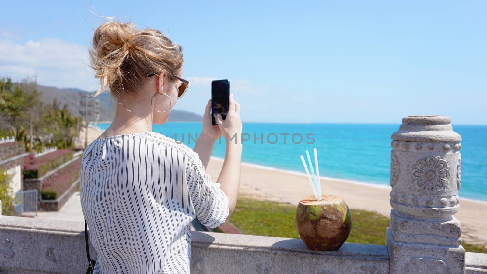 A beautiful young woman on a tropical beach with a phone in her hands. Rest, vacation, resort, beautiful life